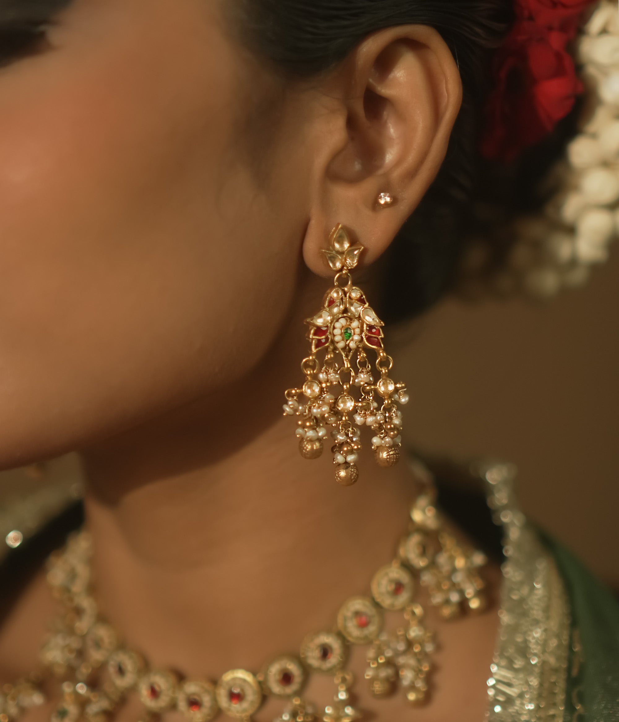 Gold-plated silver earrings with tasseled Kundan clusters, red gems, and pearls.