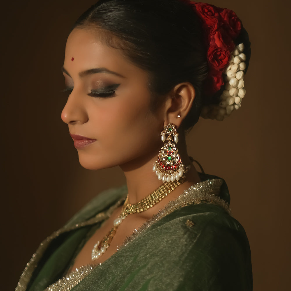 Gold teardrop earrings with red and green Kundan gems and dangling pearls.