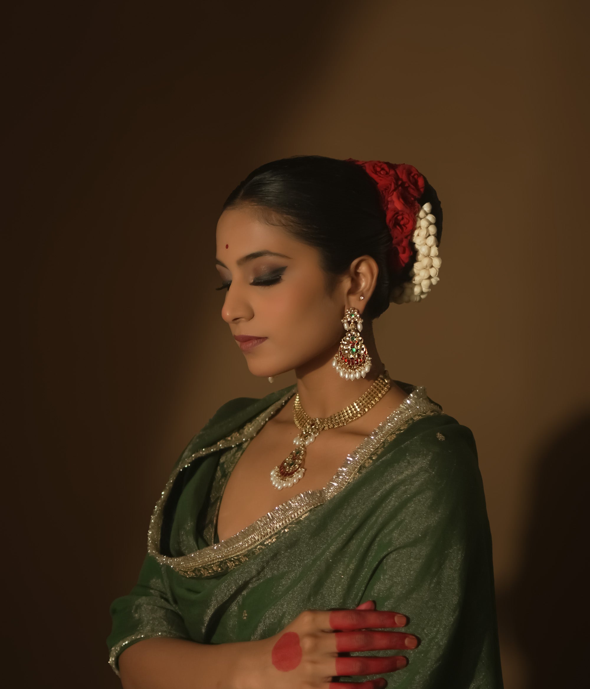 Gold teardrop earrings with red and green Kundan gems and dangling pearls.