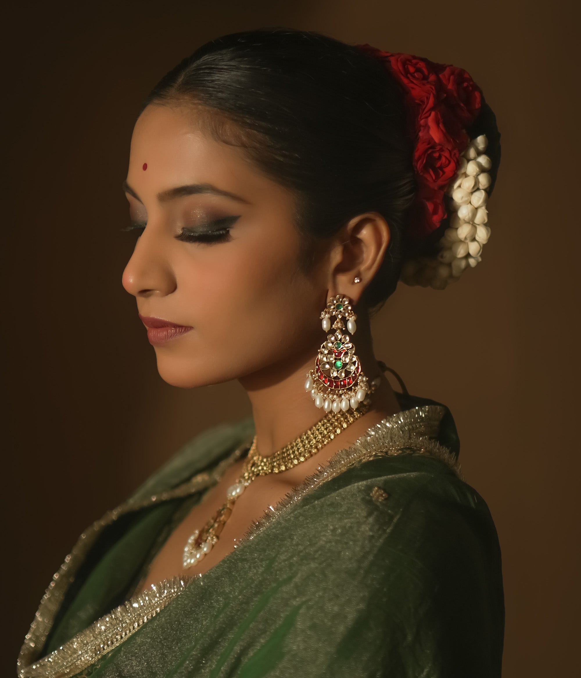 Gold teardrop earrings with red and green Kundan gems and dangling pearls.