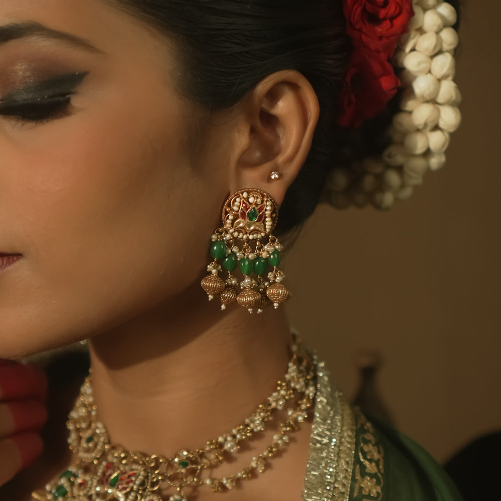 Gold jhumka earrings with green and crimson Kundan stones and pearls.