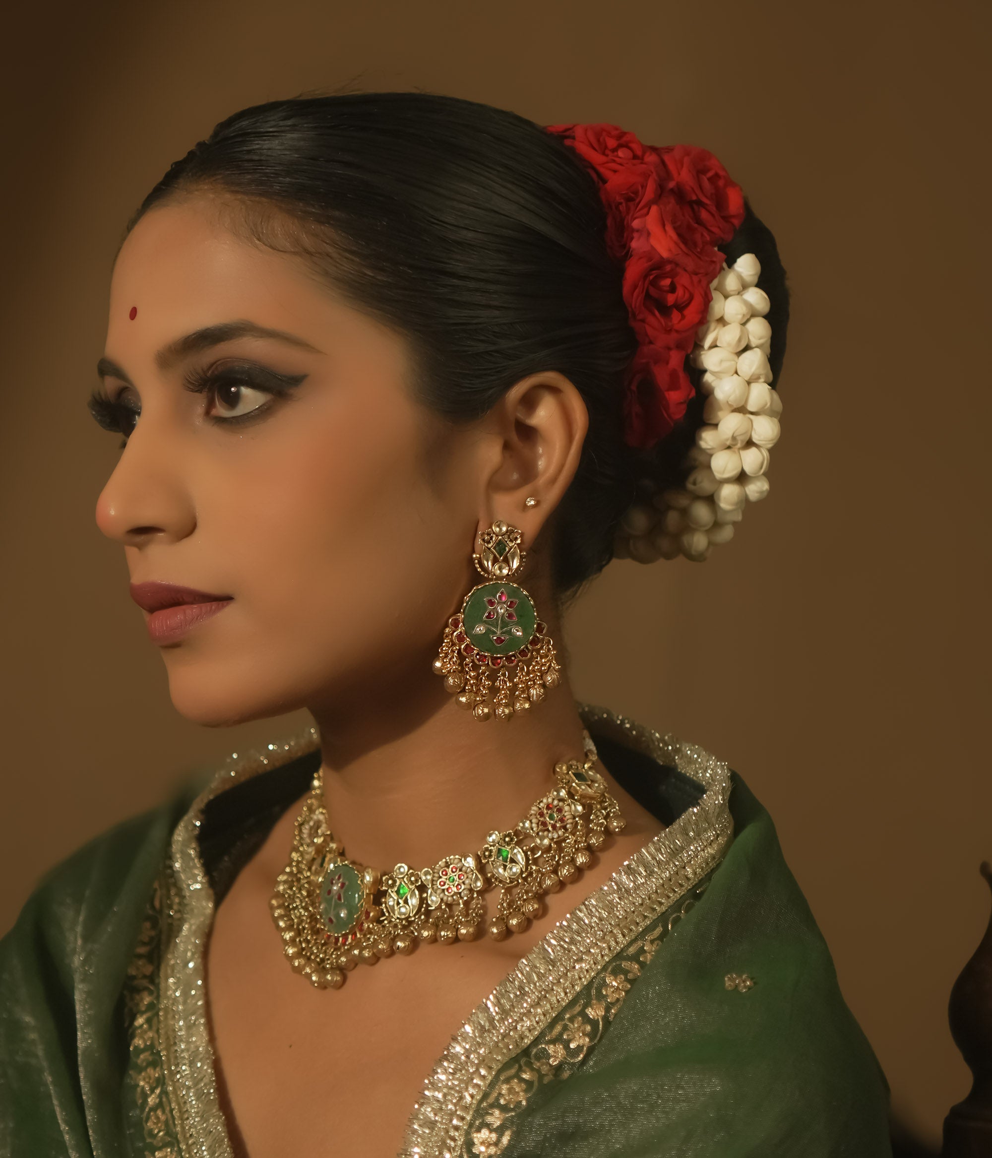 Gold-plated silver earrings with green enamel, red and clear Kundan, and tiny gold bells.