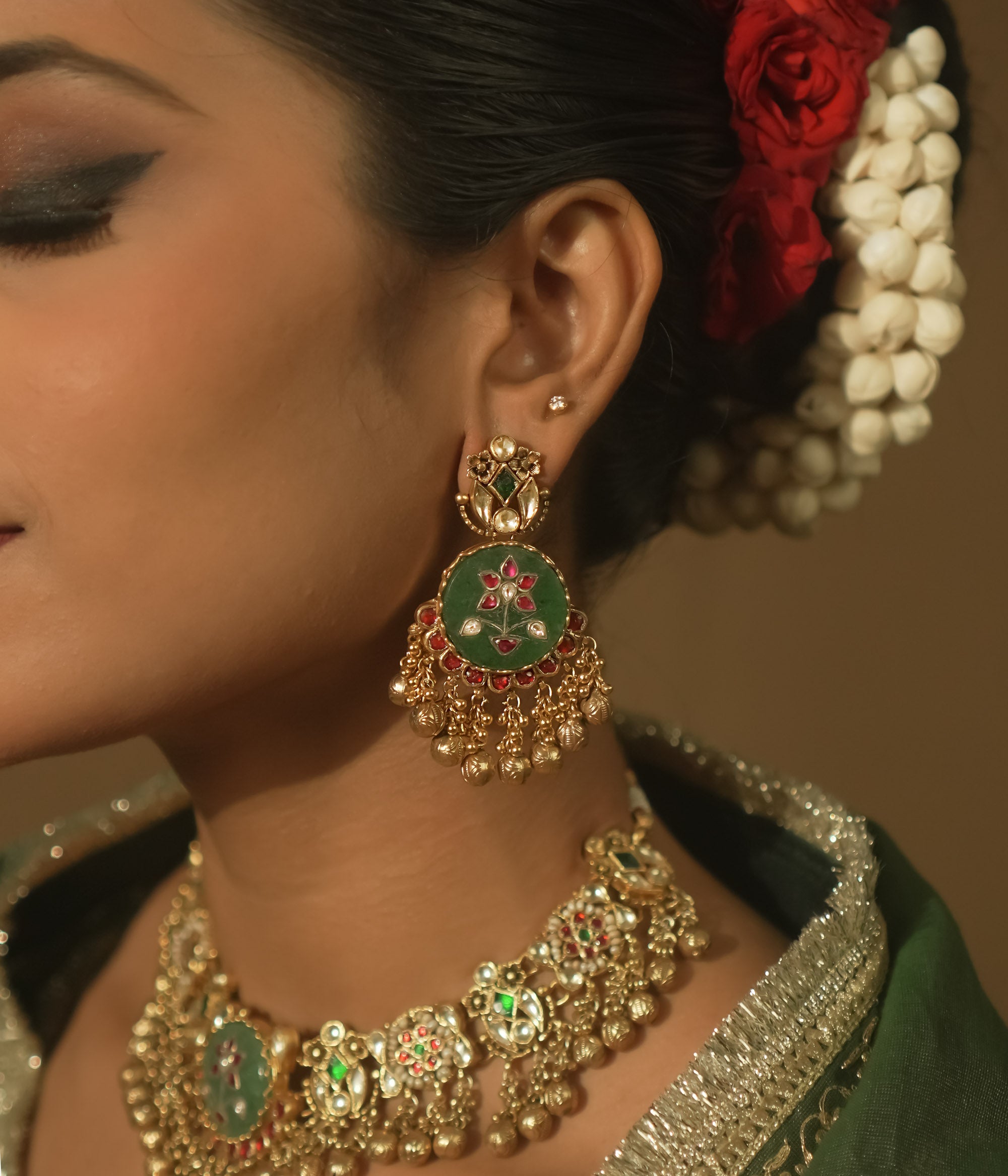 Gold-plated silver earrings with green enamel, red and clear Kundan, and tiny gold bells.