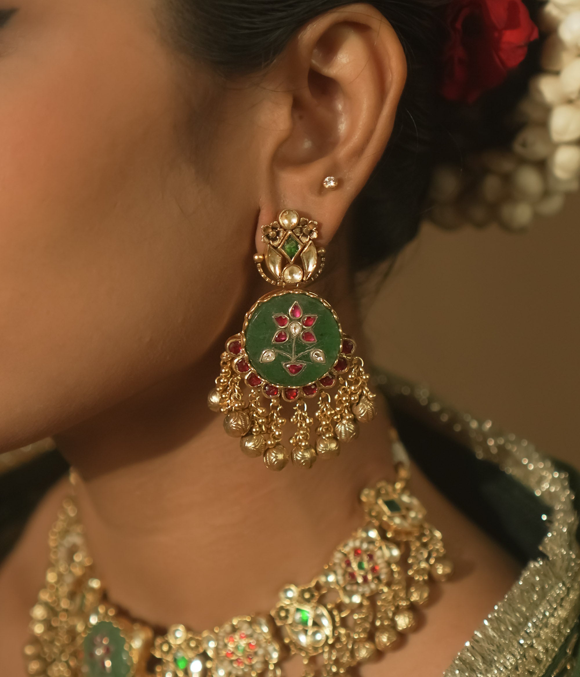 Gold-plated silver earrings with green enamel, red and clear Kundan, and tiny gold bells.