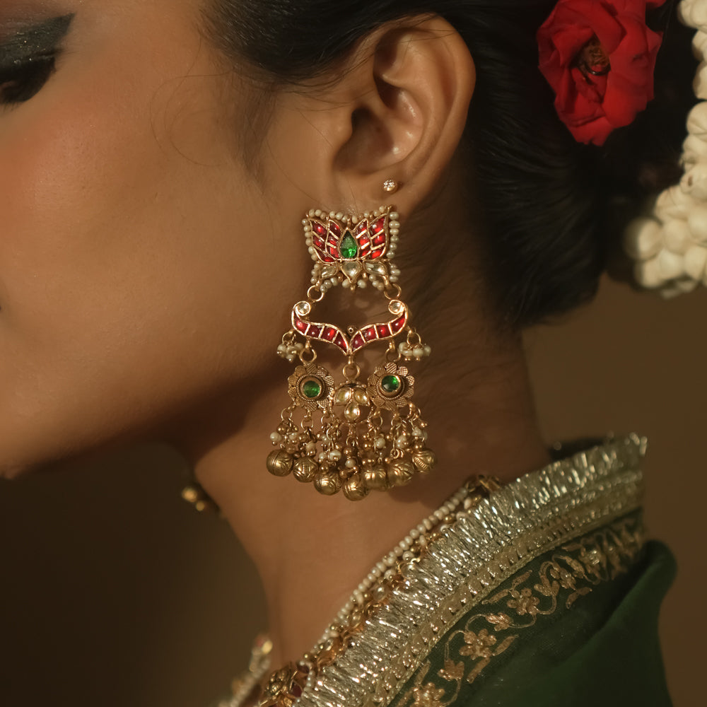 Gold earrings with red and green Kundan stones and dangling pearls.