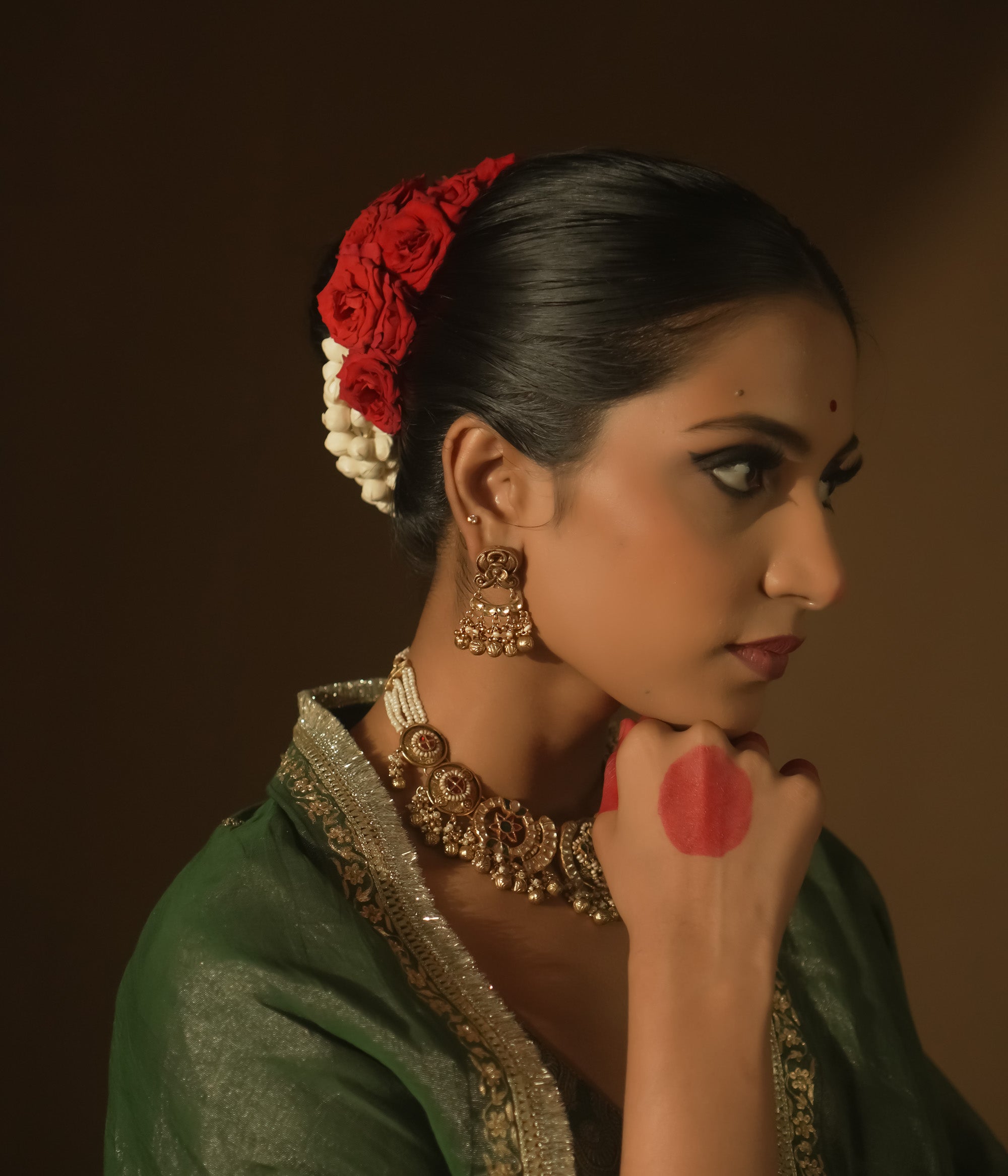 Gold chaandbali earrings with intricate swirls, red Kundan stones, and tiny bells.