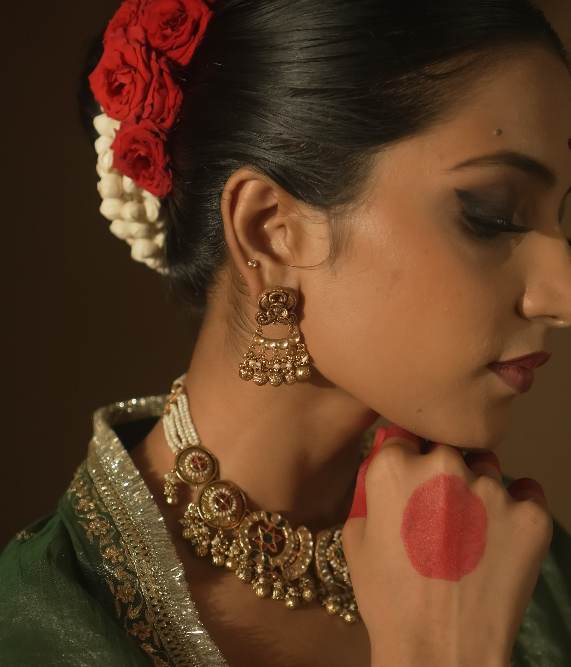 Gold chaandbali earrings with intricate swirls, red Kundan stones, and tiny bells.