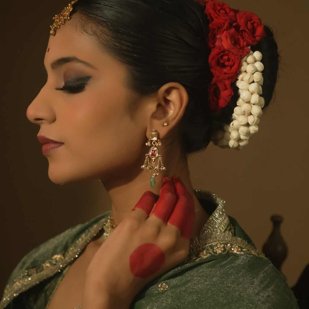 Dangling earrings with clear and red Kundan stones and teardrop emeralds.
