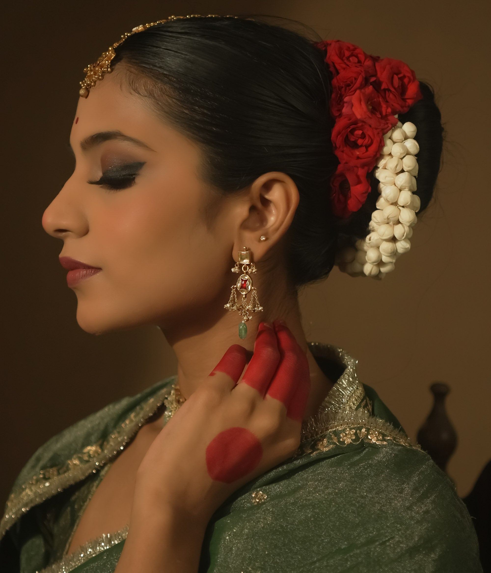 Dangling earrings with clear and red Kundan stones and teardrop emeralds.
