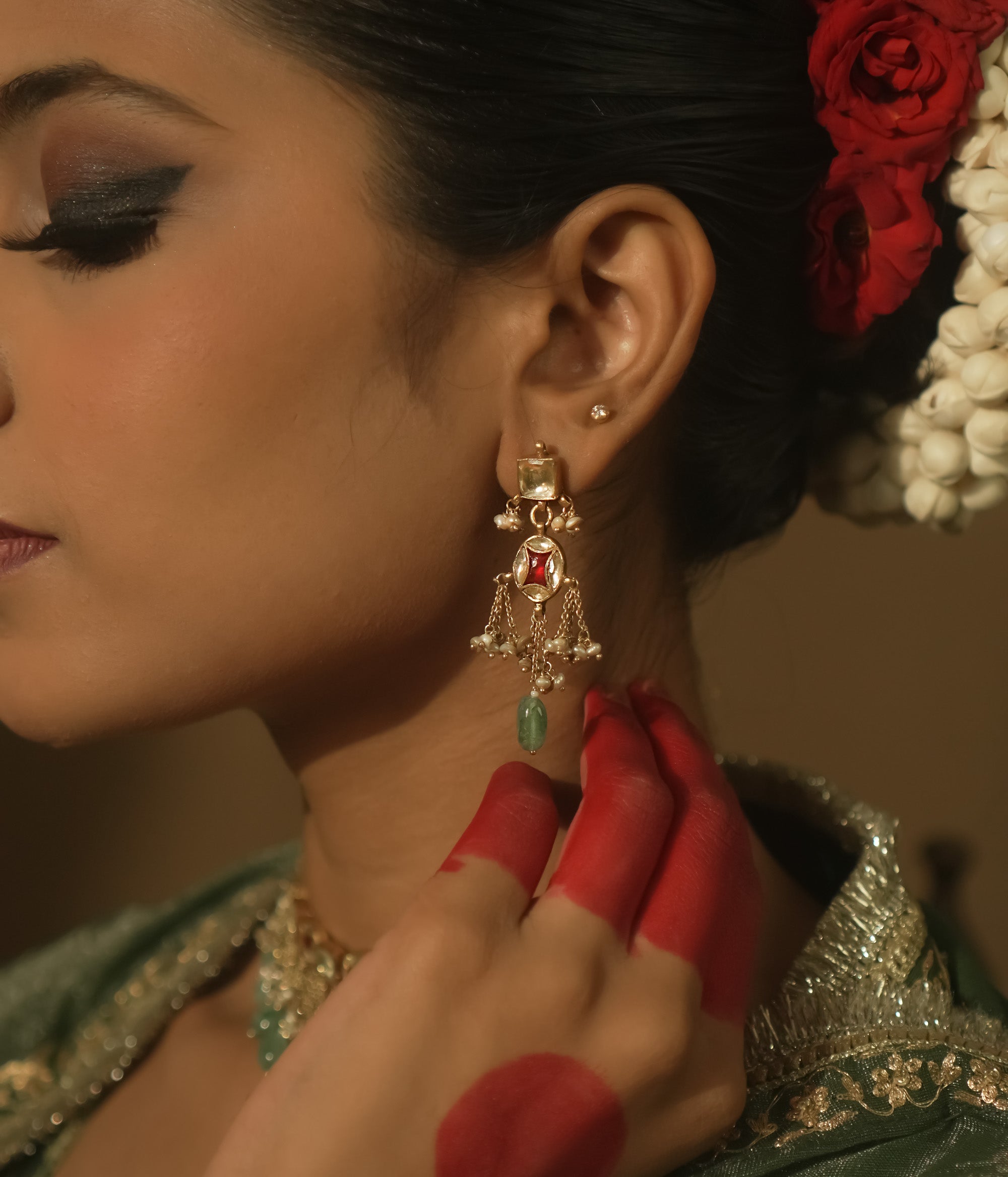 Dangling earrings with clear and red Kundan stones and teardrop emeralds.
