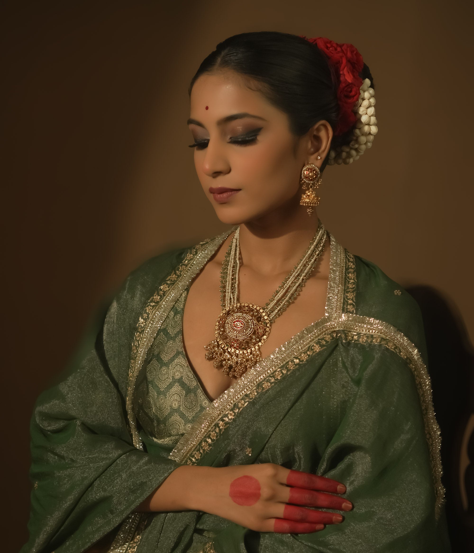 Necklace with pearls, green beads, and a central pendant with red Kundan stones.