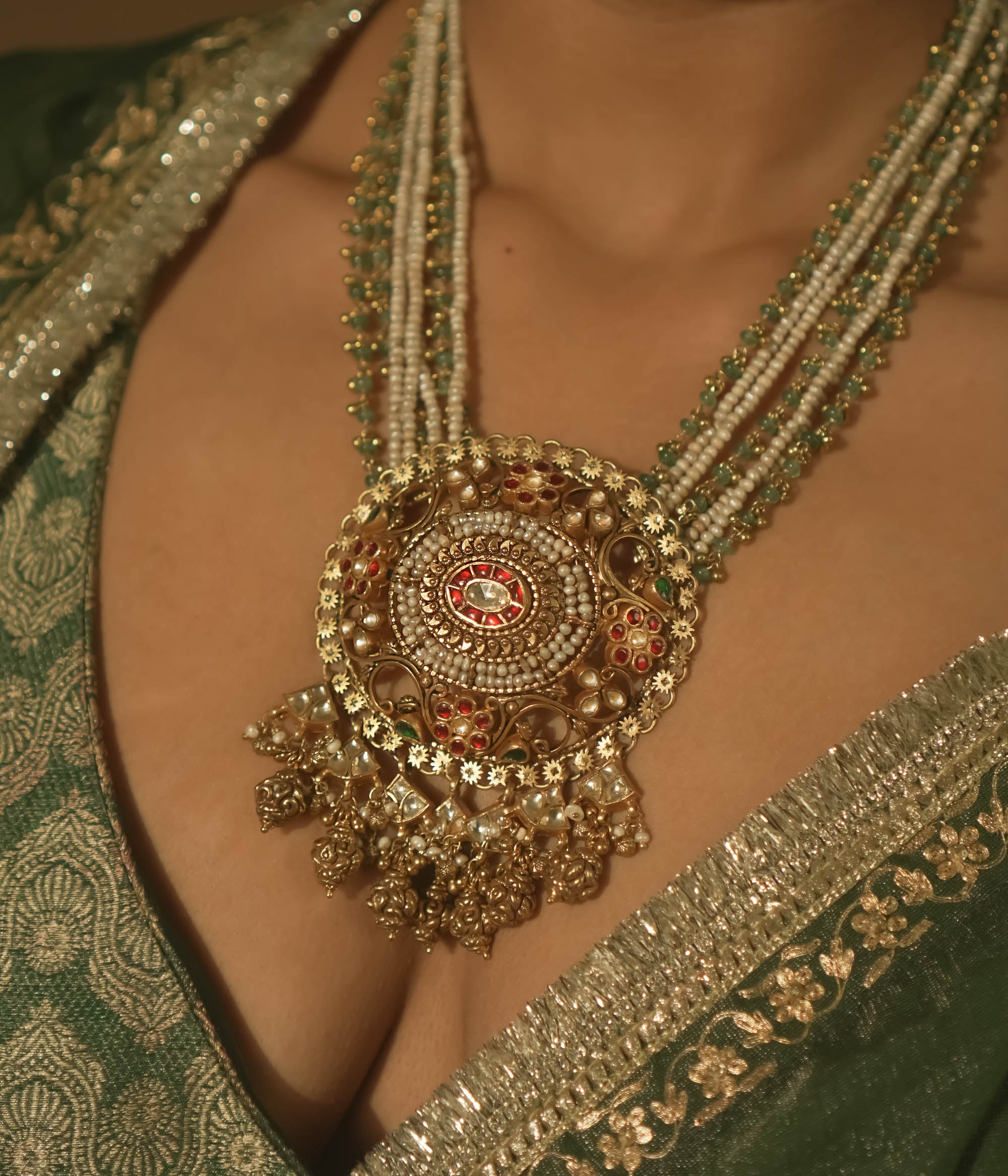 Necklace with pearls, green beads, and a central pendant with red Kundan stones.