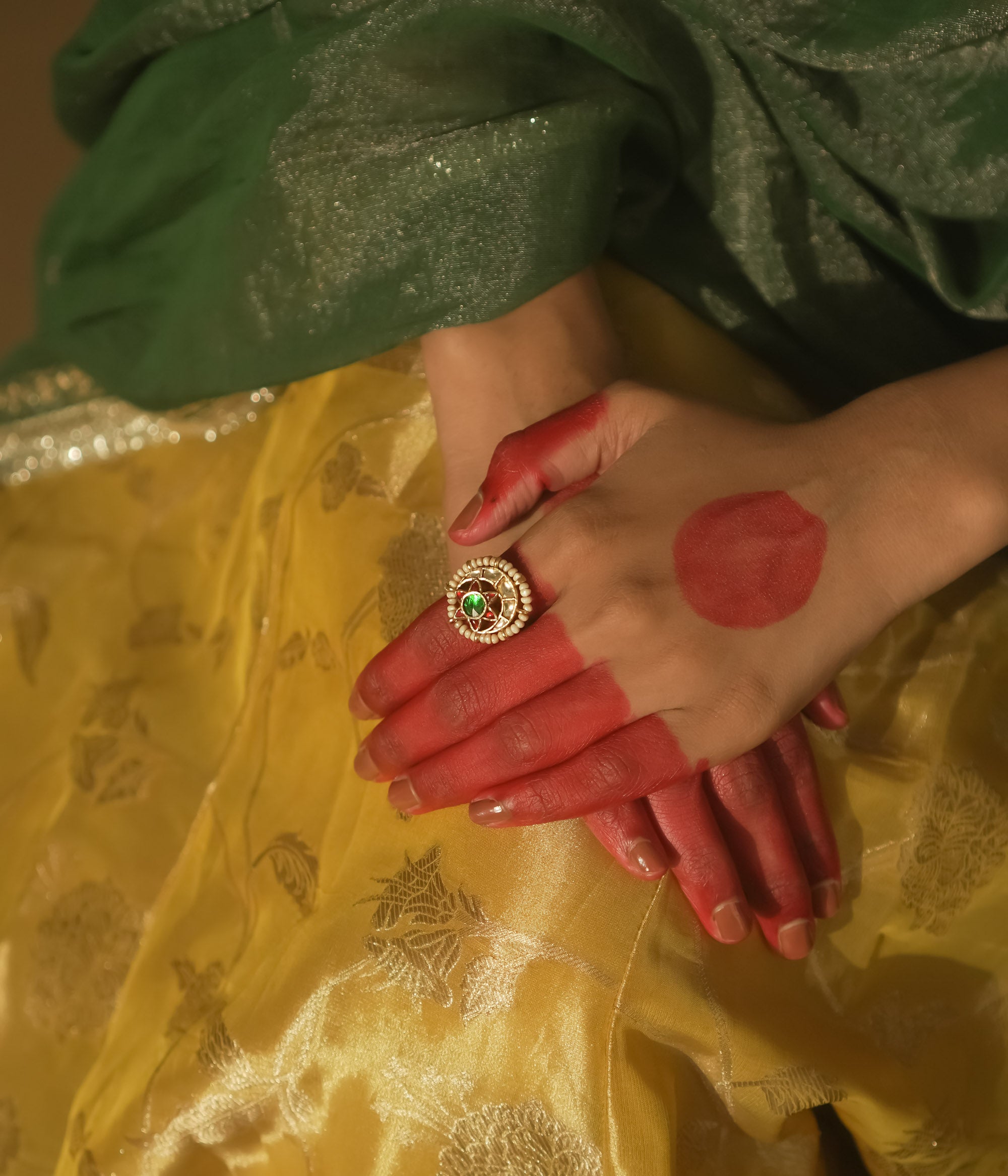 Gold-plated silver ring with a central green gem and beaded petals.