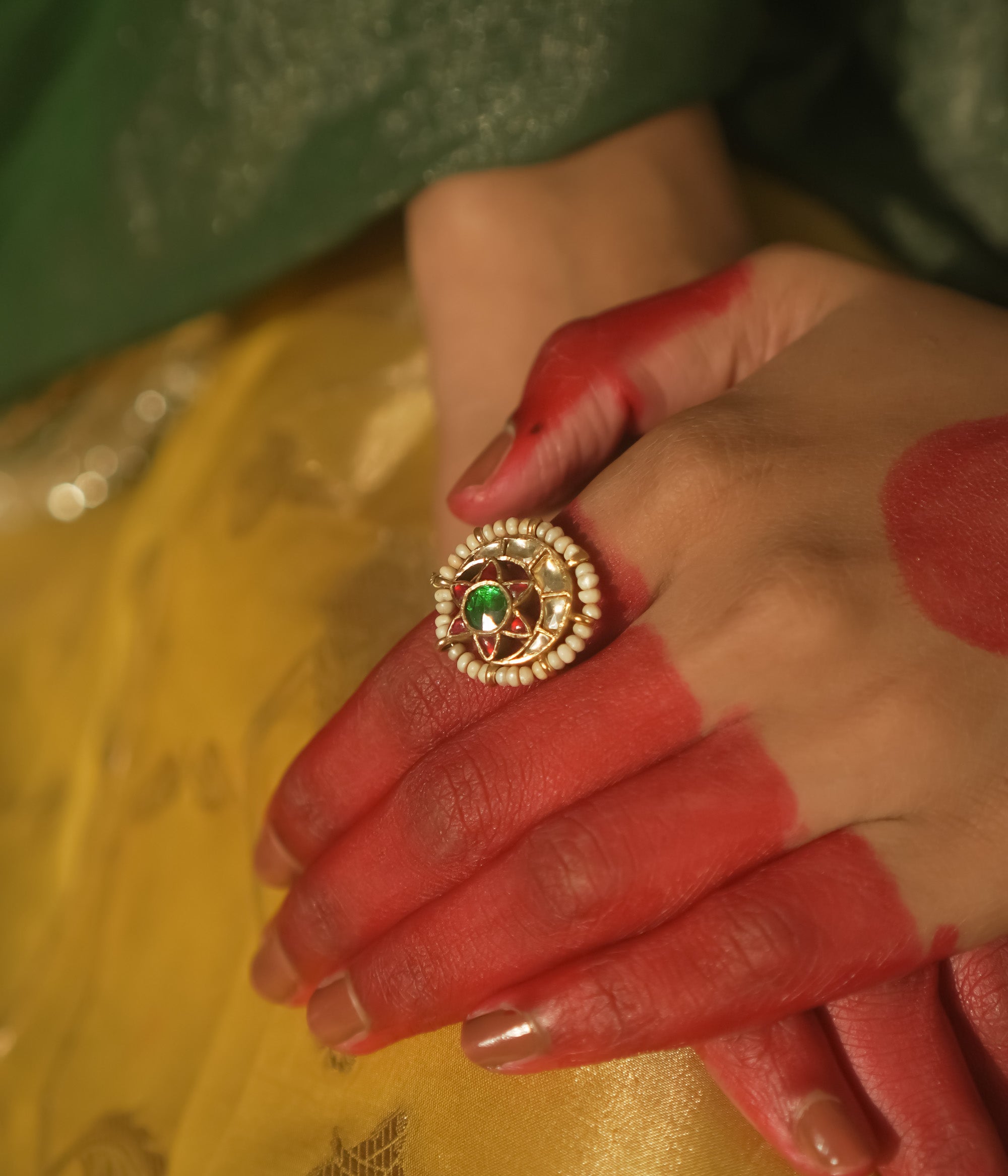 Gold-plated silver ring with a central green gem and beaded petals.