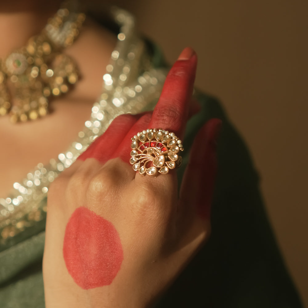 Gold-plated silver filigree ring with a central red Kundan stone and pearls.