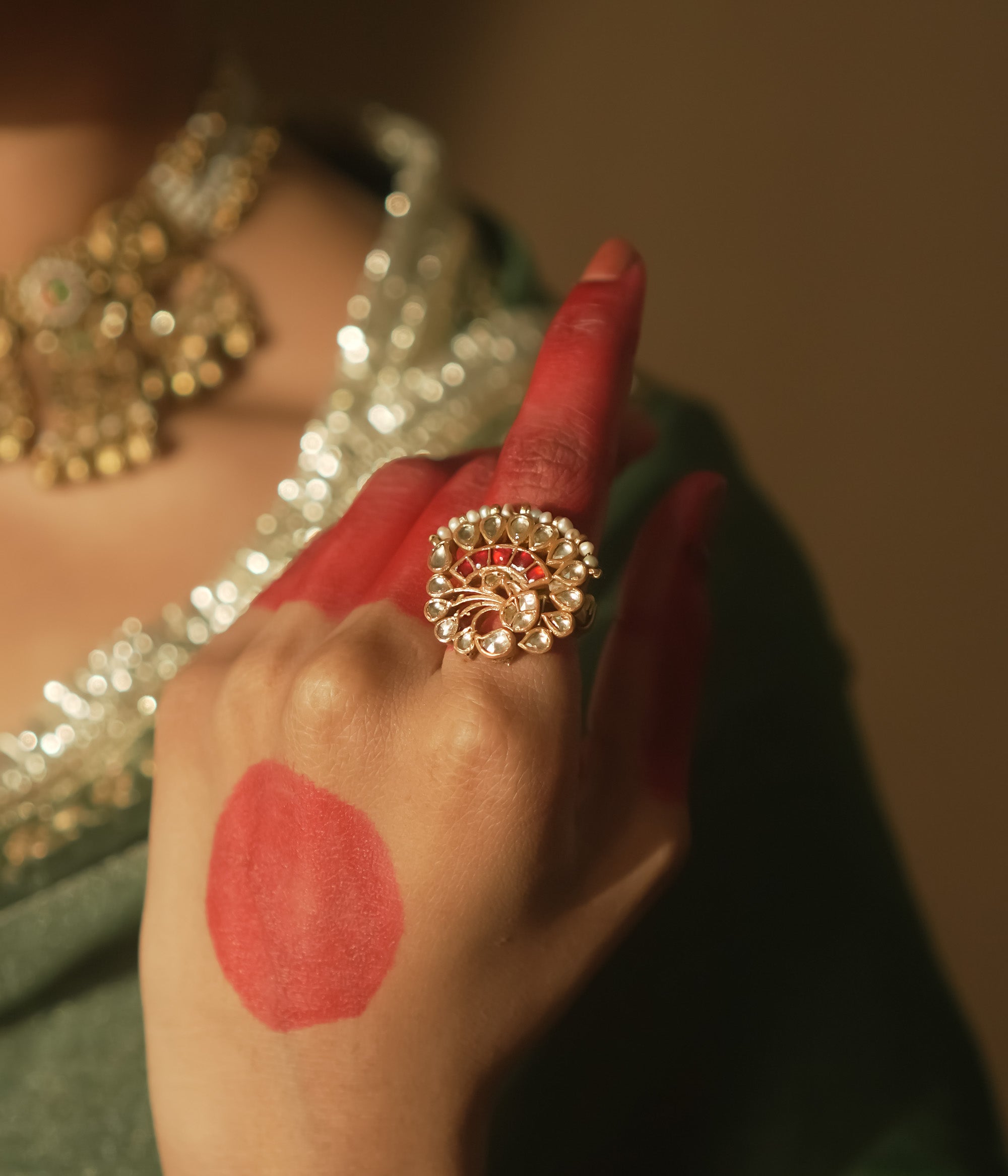 Gold-plated silver filigree ring with a central red Kundan stone and pearls.