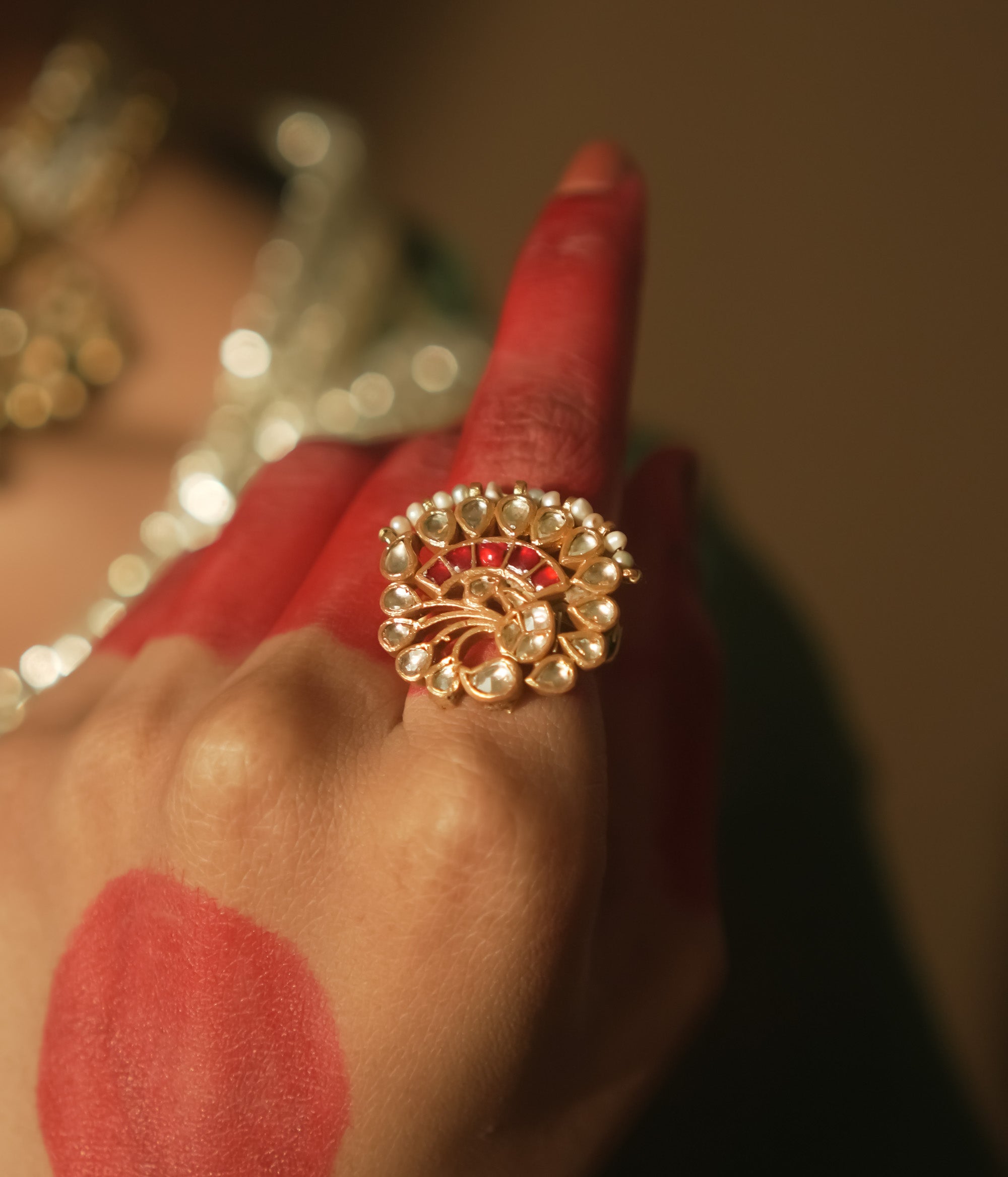 Gold-plated silver filigree ring with a central red Kundan stone and pearls.