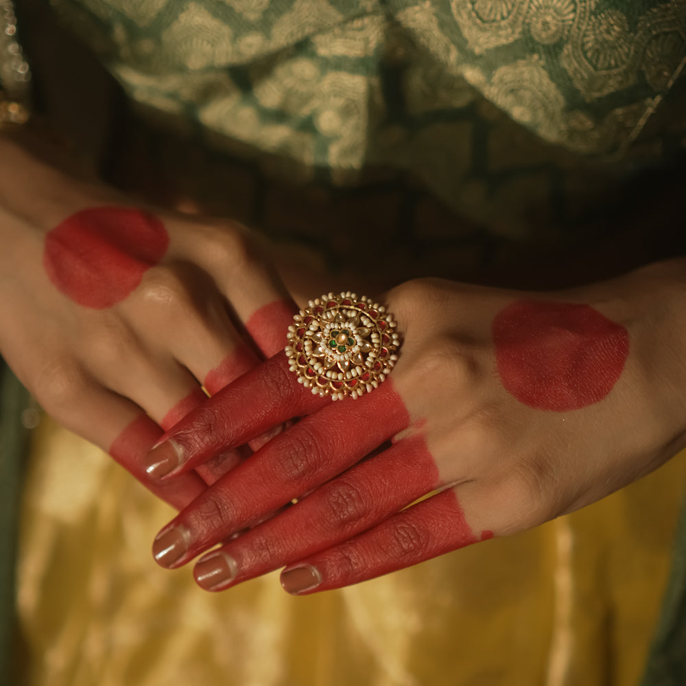 Gold-plated silver ring with filigree, pearls, and a central green Kundan stone.
