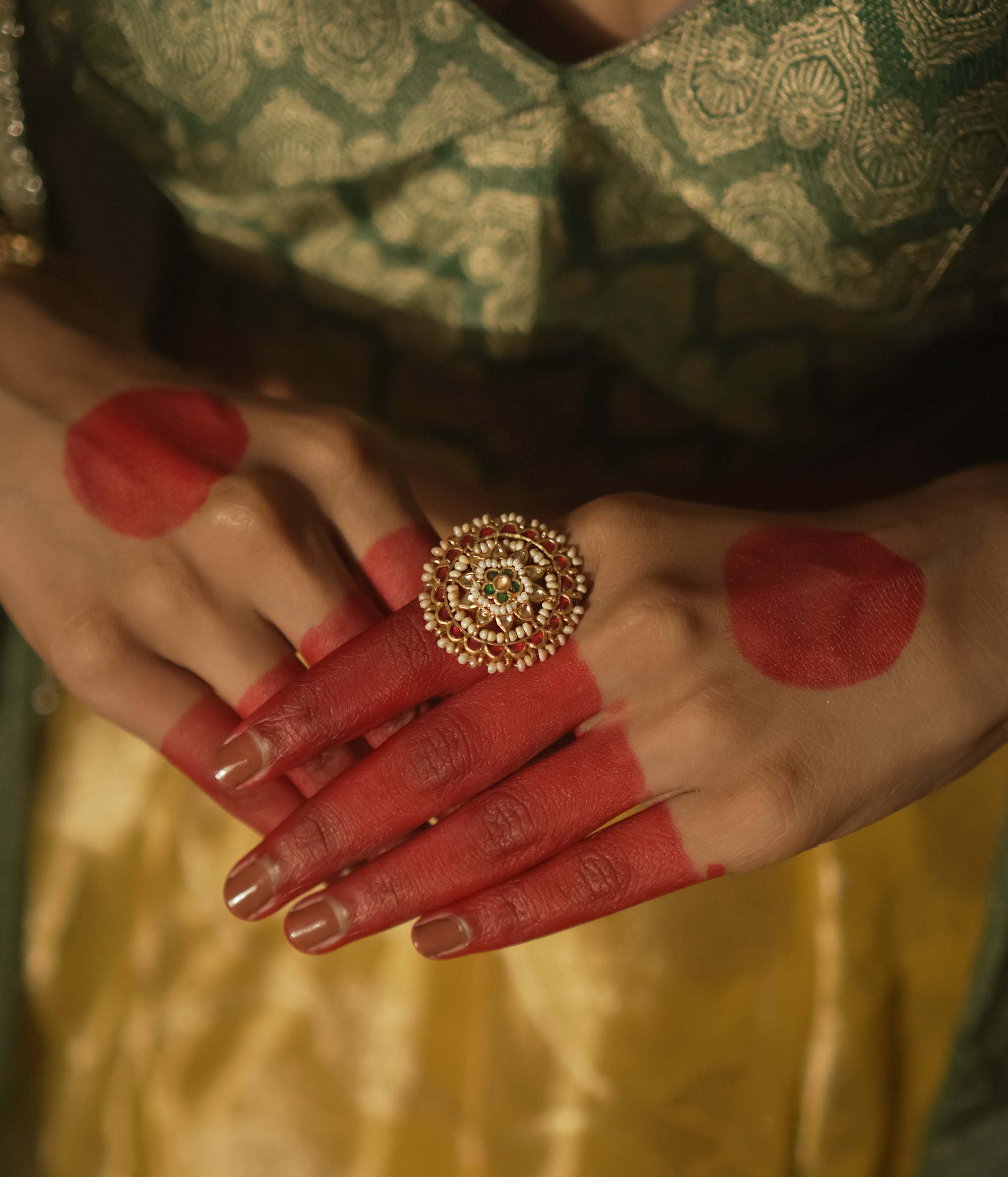 Gold-plated silver ring with filigree, pearls, and a central green Kundan stone.
