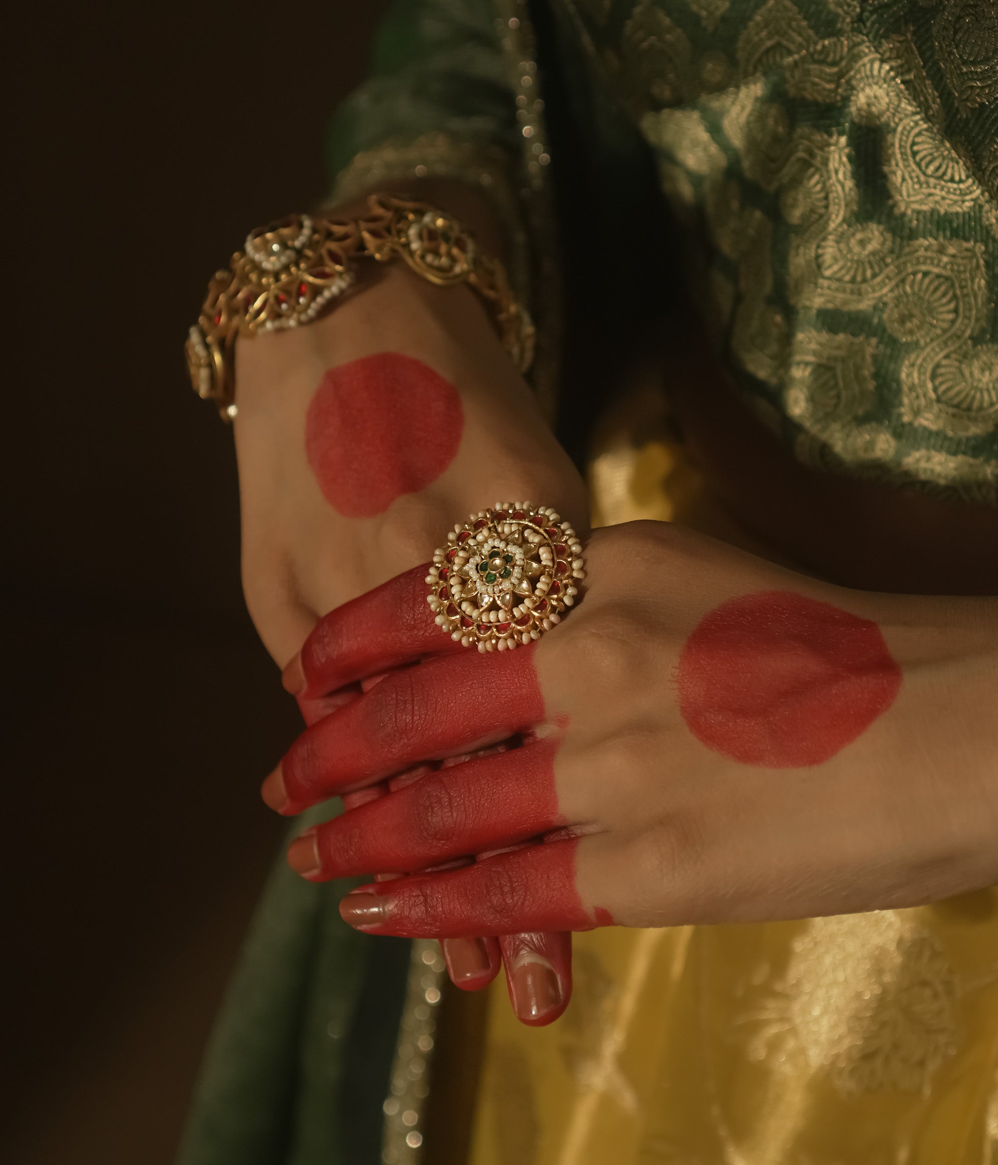 Gold-plated silver ring with filigree, pearls, and a central green Kundan stone.
