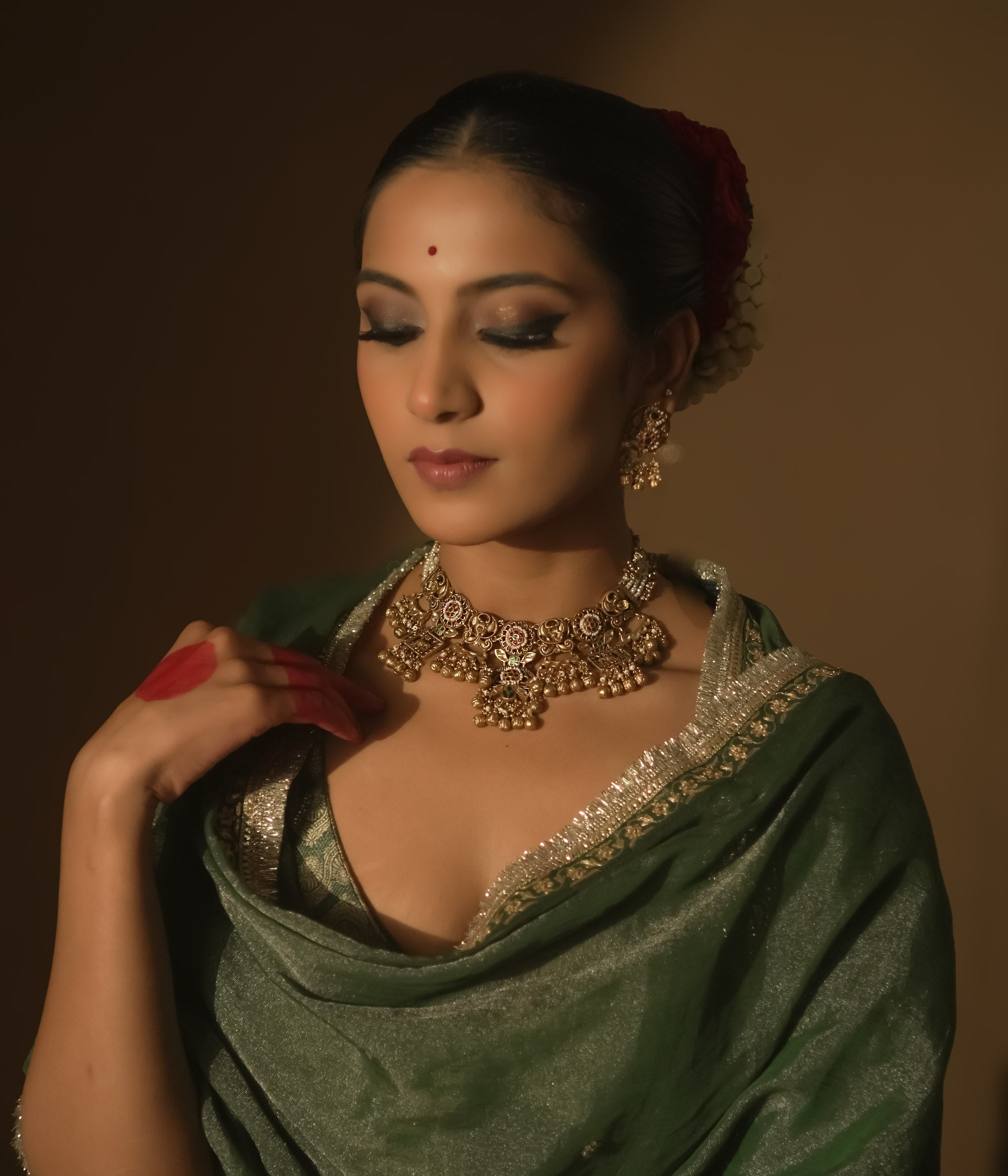 Gold-plated necklace with intricate swirls, red, green, and white gems, pearls, and bells.