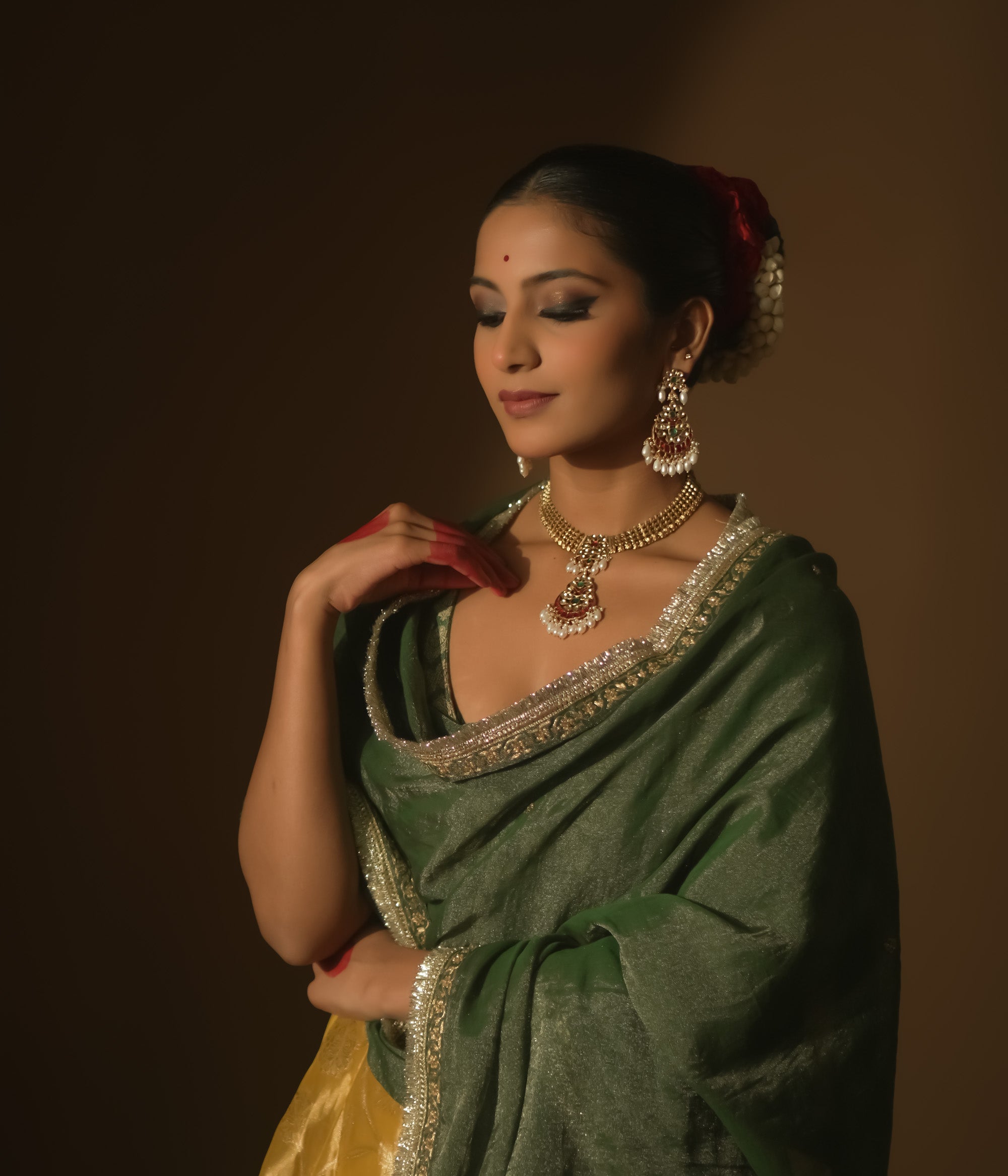 Gold necklace with a central pendant, rubies, emeralds, and dangling pearls.