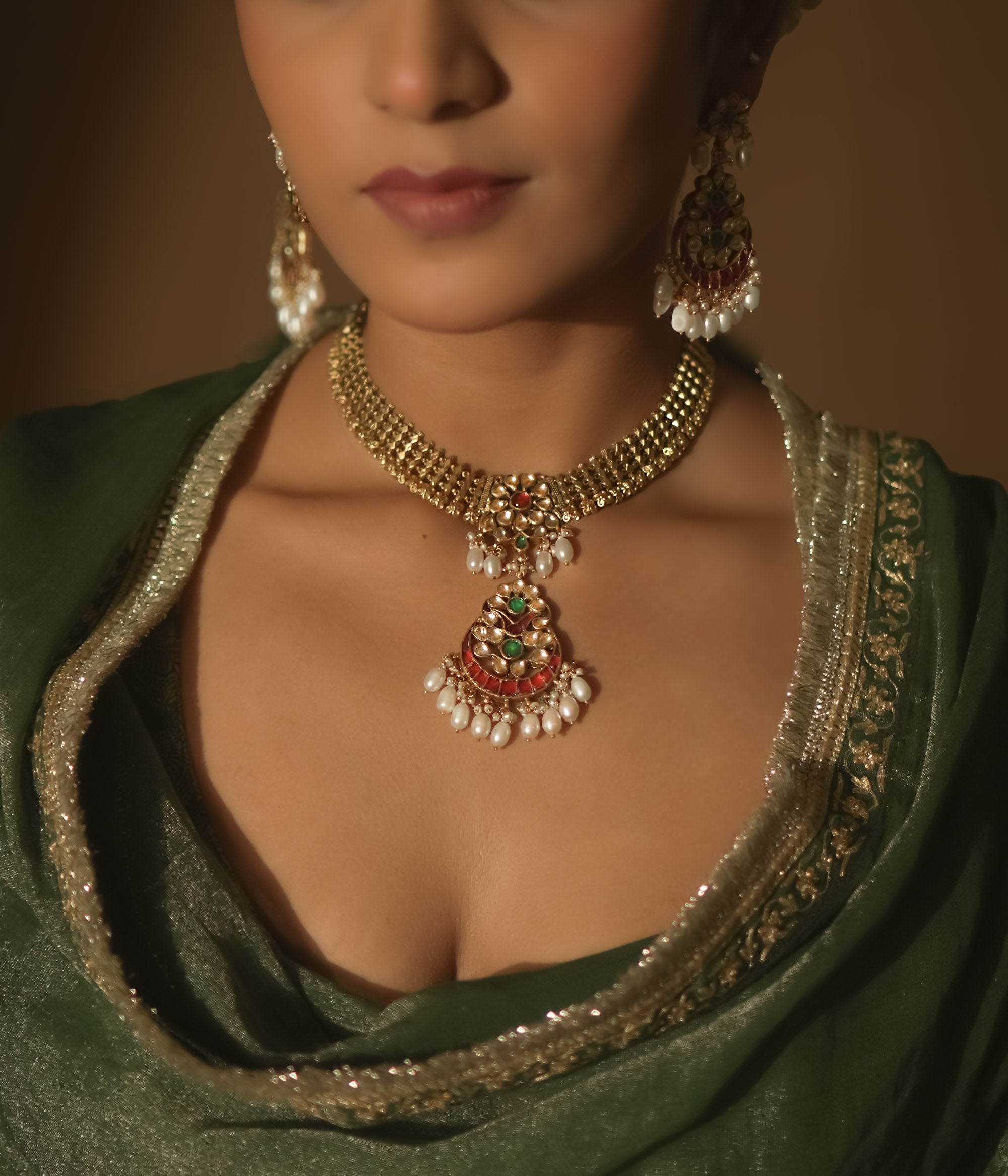 Gold necklace with a central pendant, rubies, emeralds, and dangling pearls.
