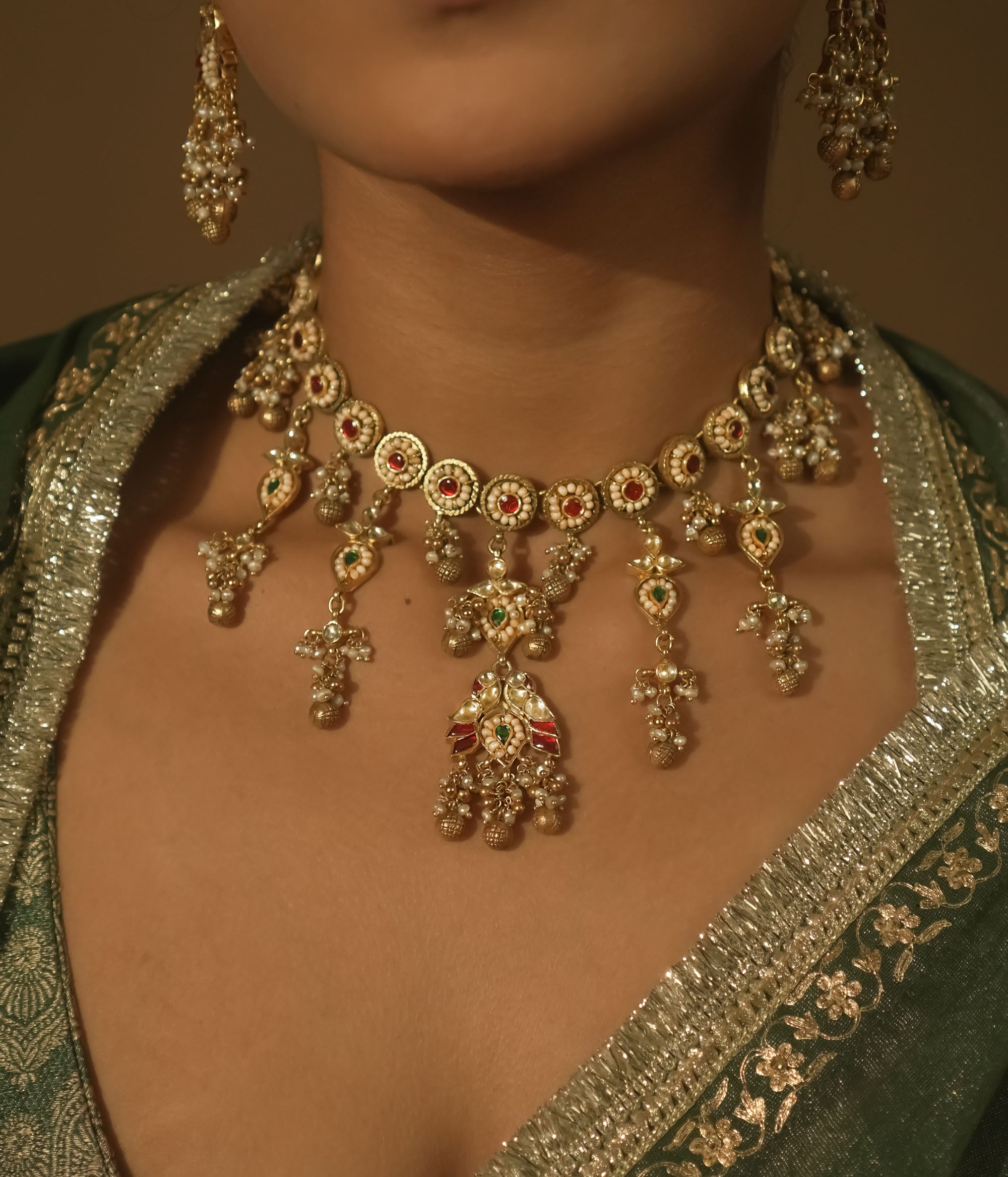 Gold-plated silver necklace with intricate loops, green Kundan, and pearls.
