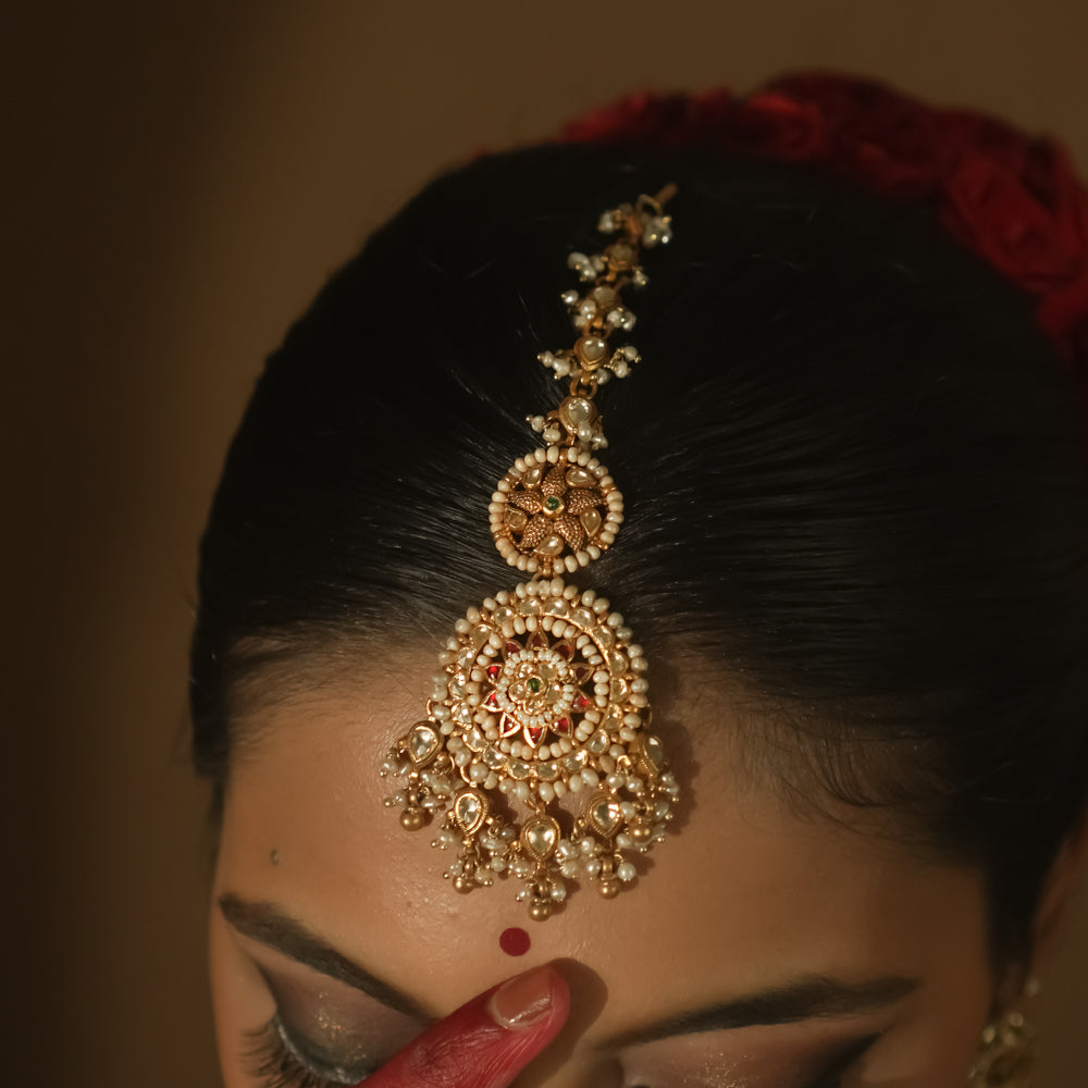 Gold maangtika with filigree, Kundan stones, and a large medallion with pearl drops.