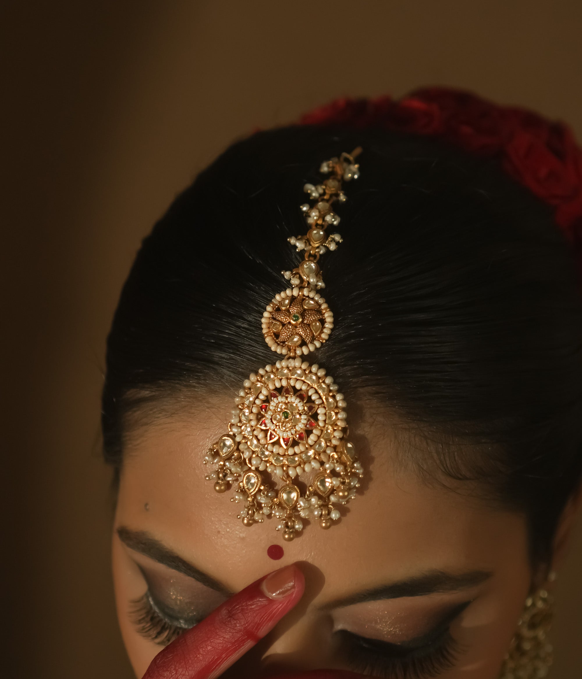 Gold maangtika with filigree, Kundan stones, and a large medallion with pearl drops.