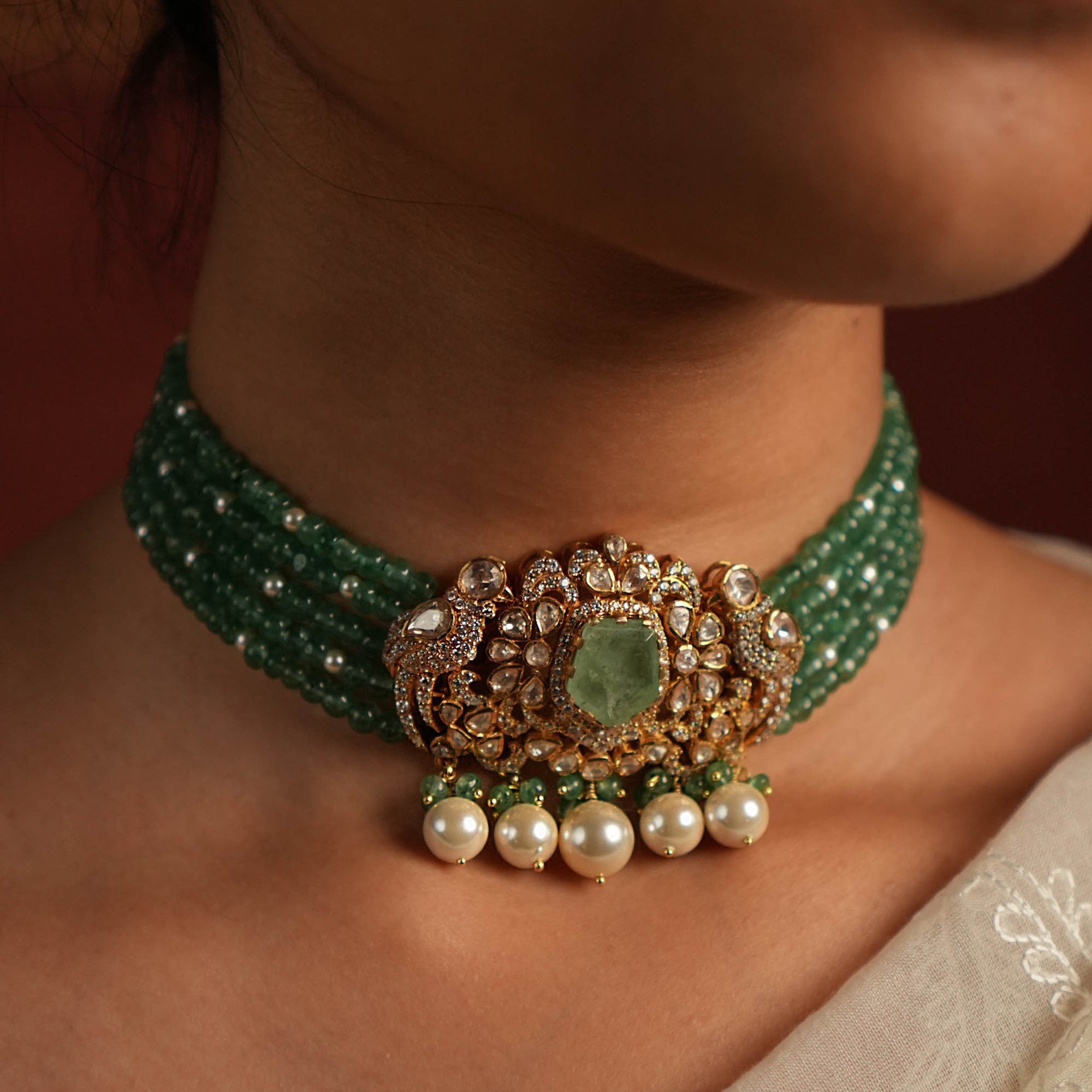 Close-up of a green beaded necklace with a decorative clasp on a person's neck.