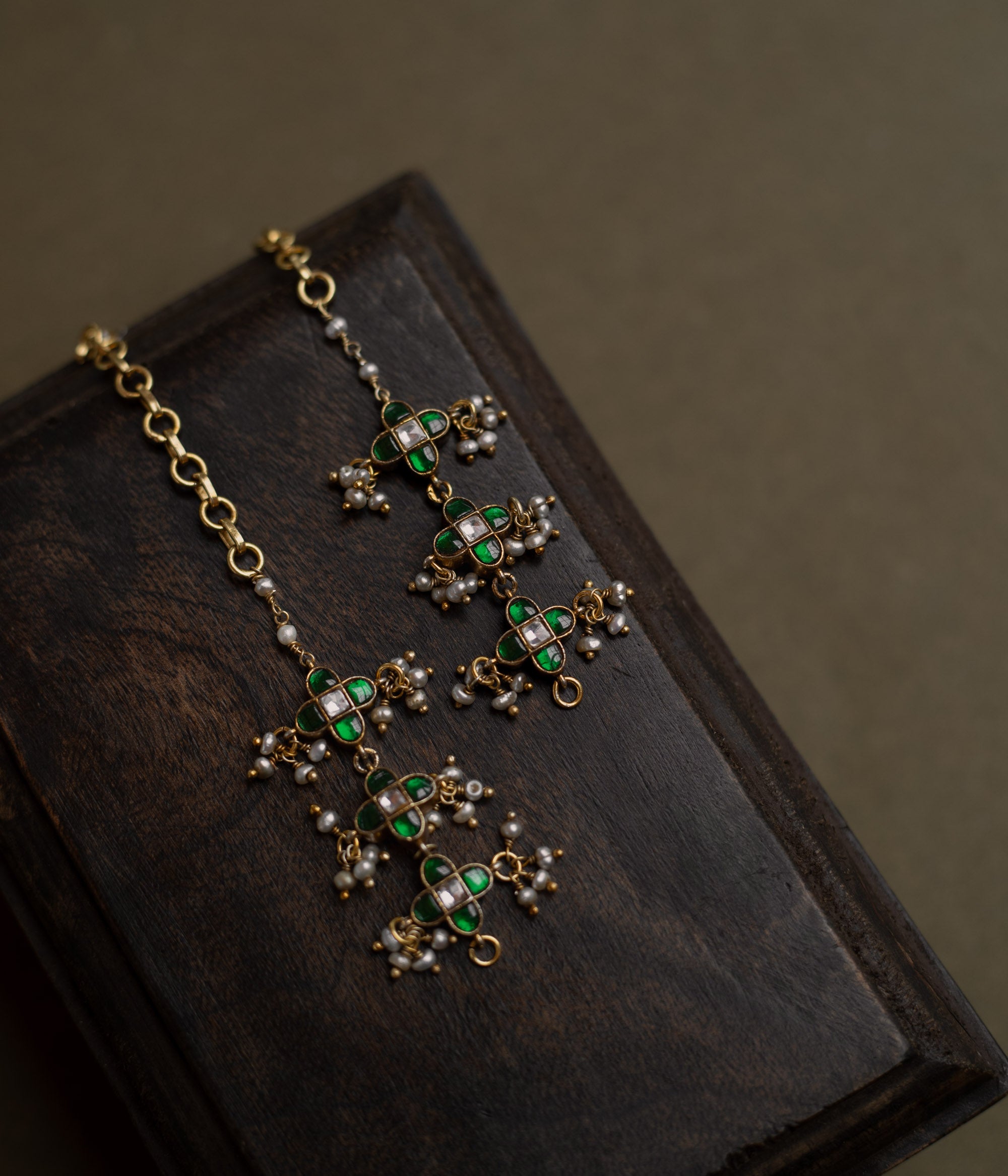 Kundan Collection ear chain with green kundan, white kundan, and pearls in floral-inspired meadow design.