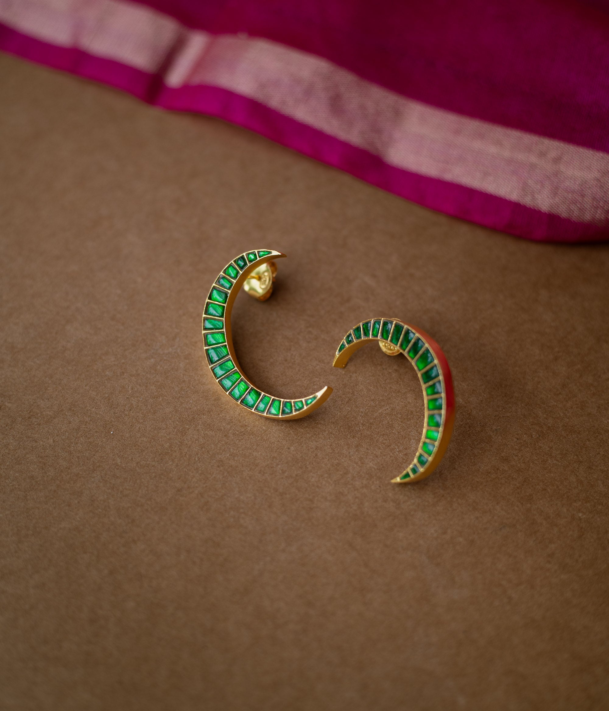 A pair of green Kundan drop earrings with intricate patterns.