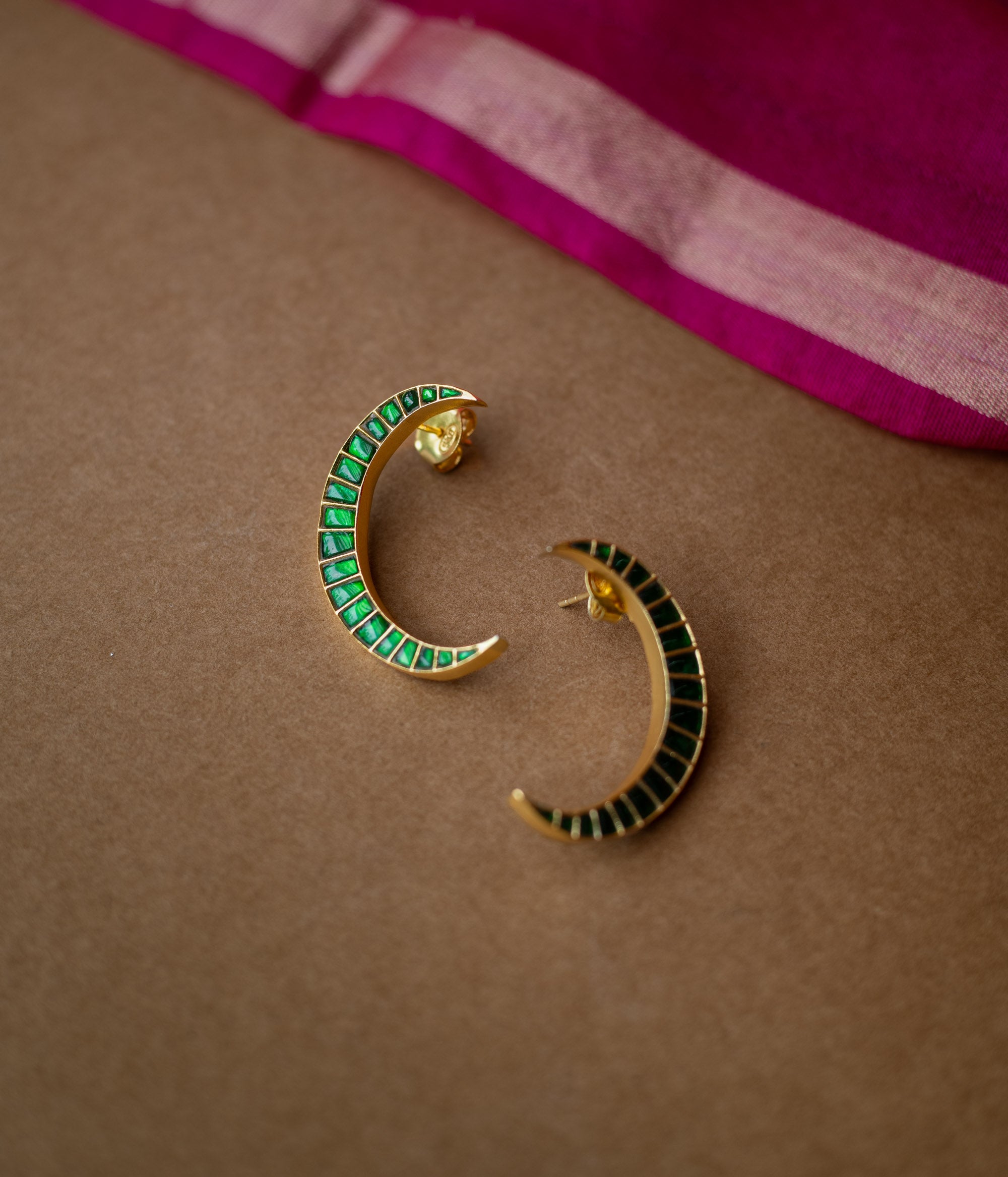 A pair of green Kundan drop earrings with intricate patterns.