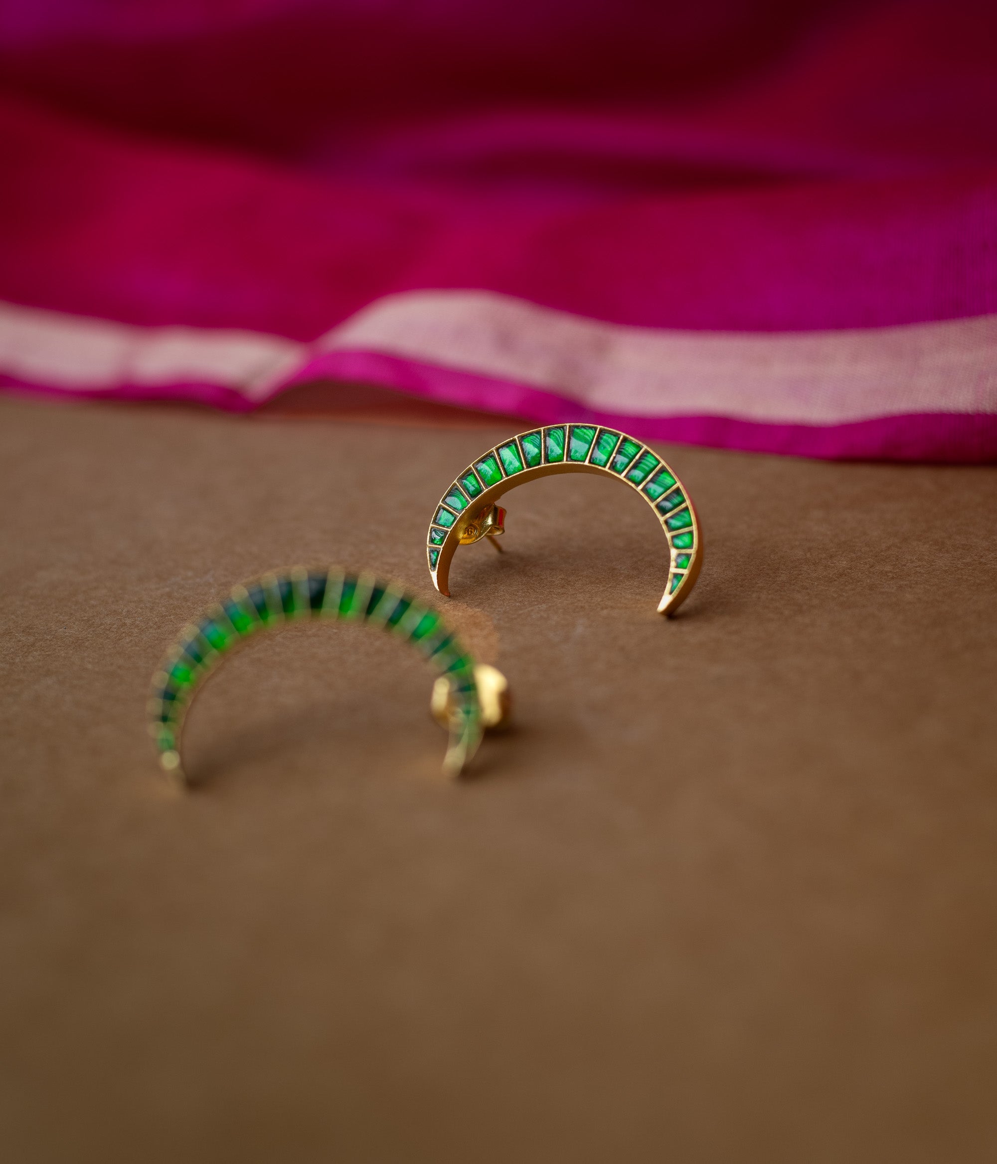 A pair of green Kundan drop earrings with intricate patterns.