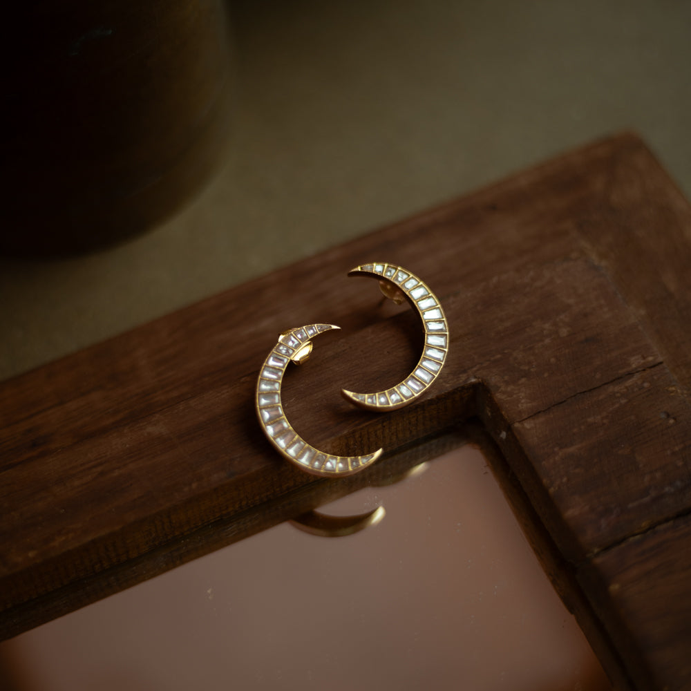 Crescent-shaped Kundan earrings with white stones set in gold, inspired by moonlit elegance.