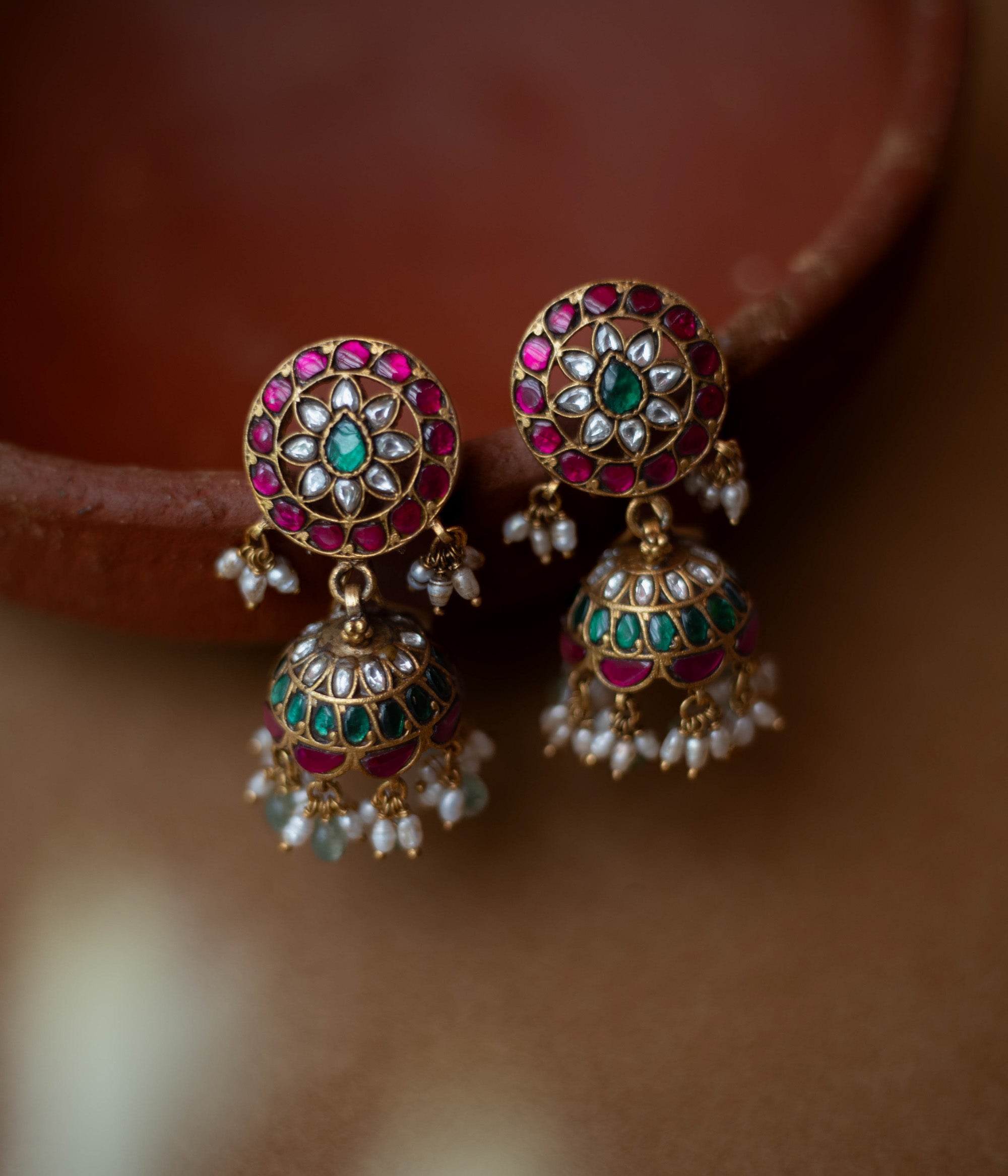 Round floral Kundan earrings with dome-shaped jhumkas, pearls, and green bead hangings.
