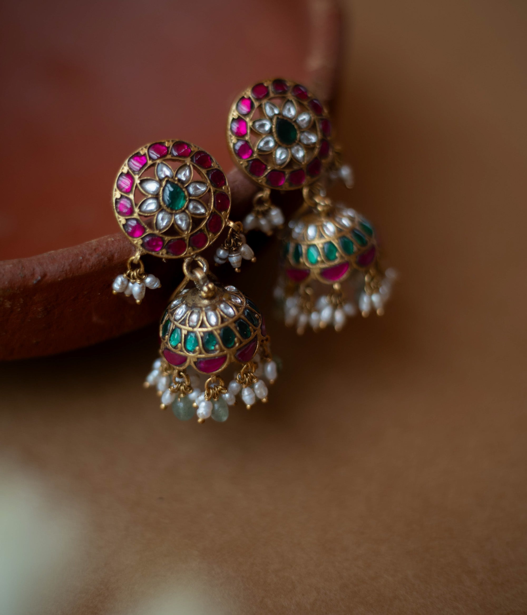 Round floral Kundan earrings with dome-shaped jhumkas, pearls, and green bead hangings.