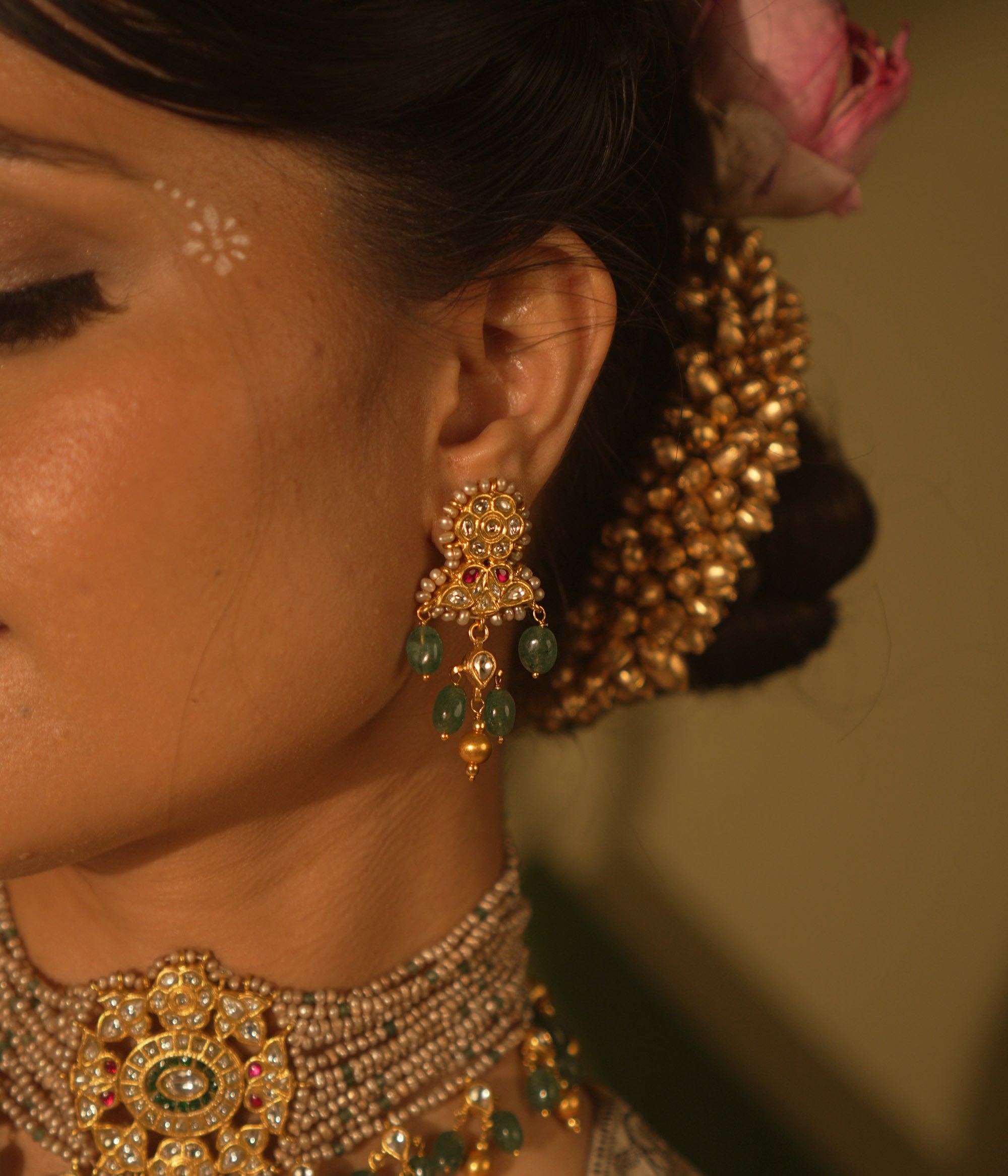 Gold-toned Kundan earrings with red and white stones, green bead drops, and pearl accents—traditional and regal design.