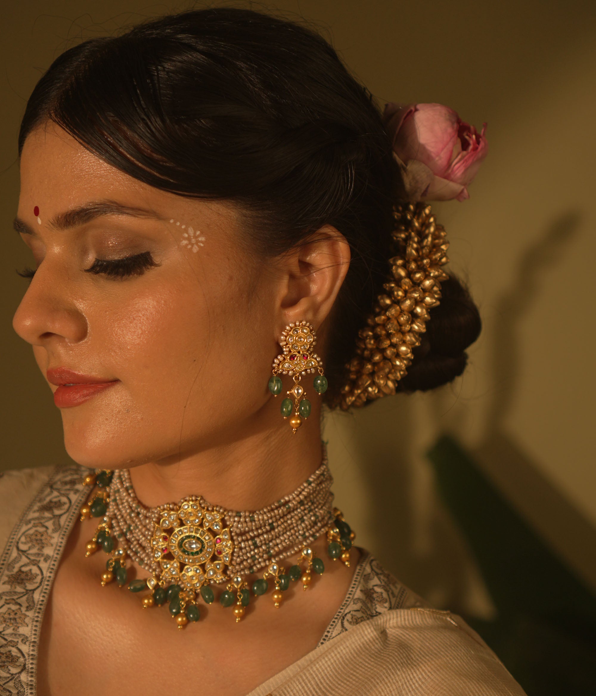 Gold-toned Kundan earrings with red and white stones, green bead drops, and pearl accents—traditional and regal design.