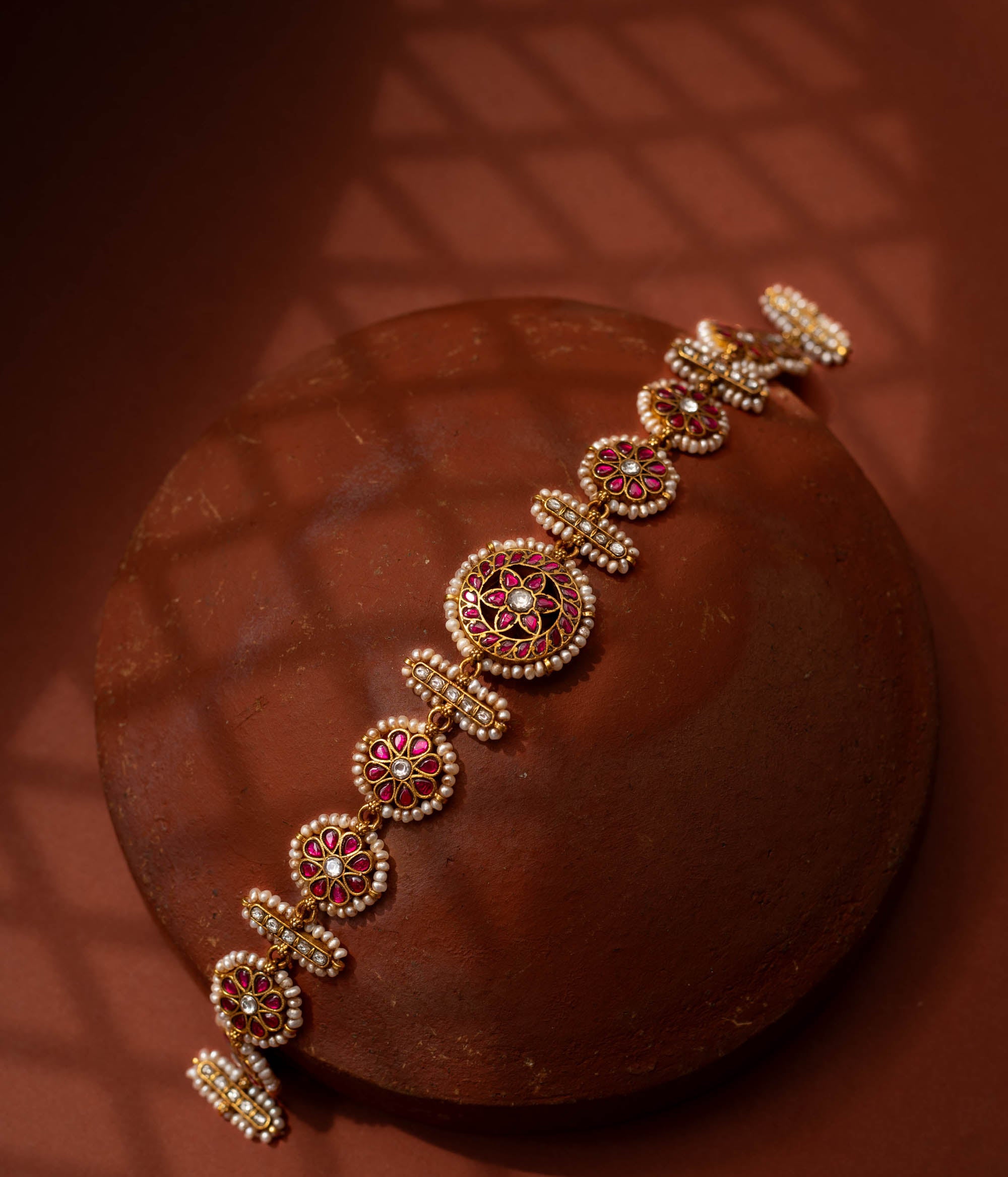 Stunning 92.5 sterling silver Rangoli Radiance Pearl Mathapatti inspired by festive rangoli patterns, crafted with circular ruby red and kundan stone motifs bordered by delicate pearls, perfect for bridal looks, temple ceremonies, or cultural festivities, blending elegance with heritage.