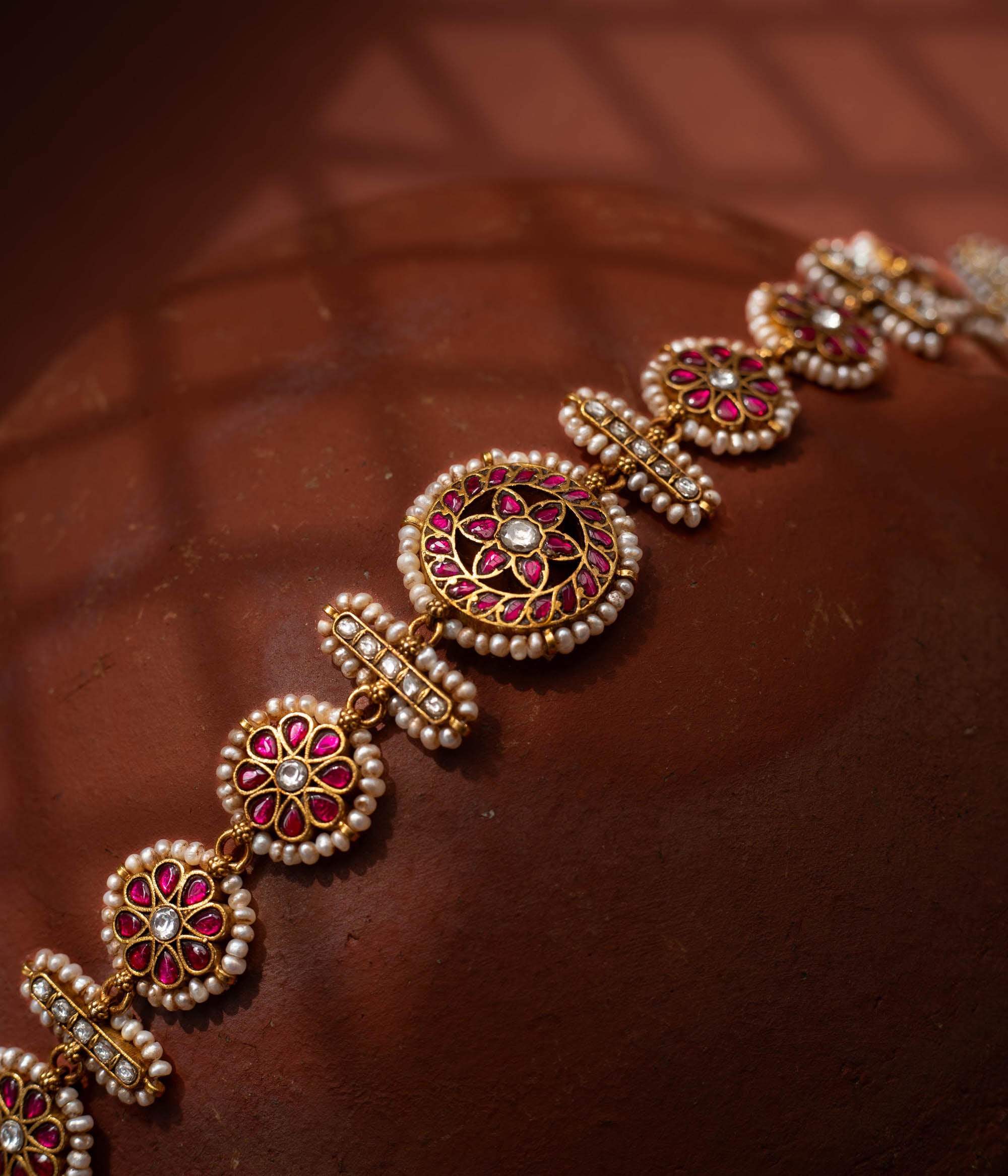 Stunning 92.5 sterling silver Rangoli Radiance Pearl Mathapatti inspired by festive rangoli patterns, crafted with circular ruby red and kundan stone motifs bordered by delicate pearls, perfect for bridal looks, temple ceremonies, or cultural festivities, blending elegance with heritage.