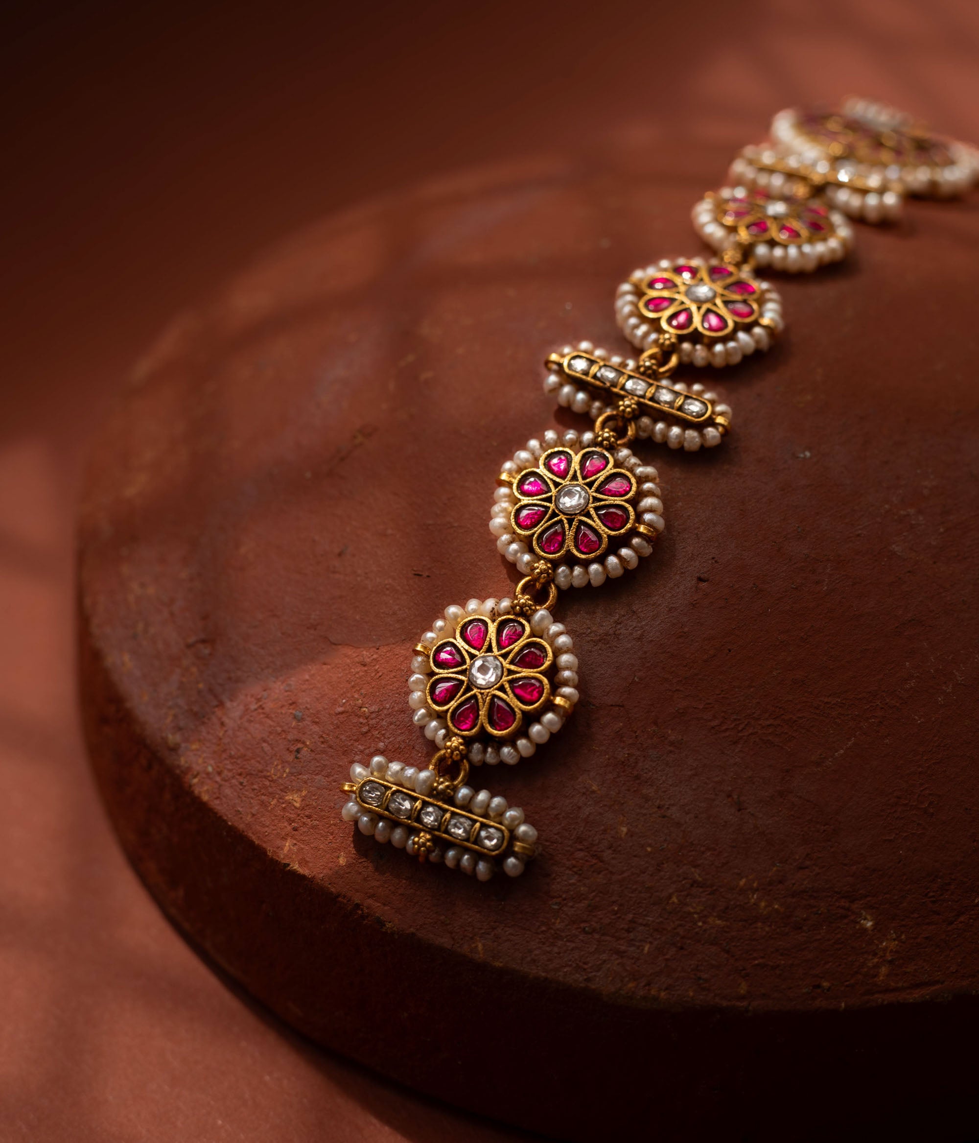 Stunning 92.5 sterling silver Rangoli Radiance Pearl Mathapatti inspired by festive rangoli patterns, crafted with circular ruby red and kundan stone motifs bordered by delicate pearls, perfect for bridal looks, temple ceremonies, or cultural festivities, blending elegance with heritage.