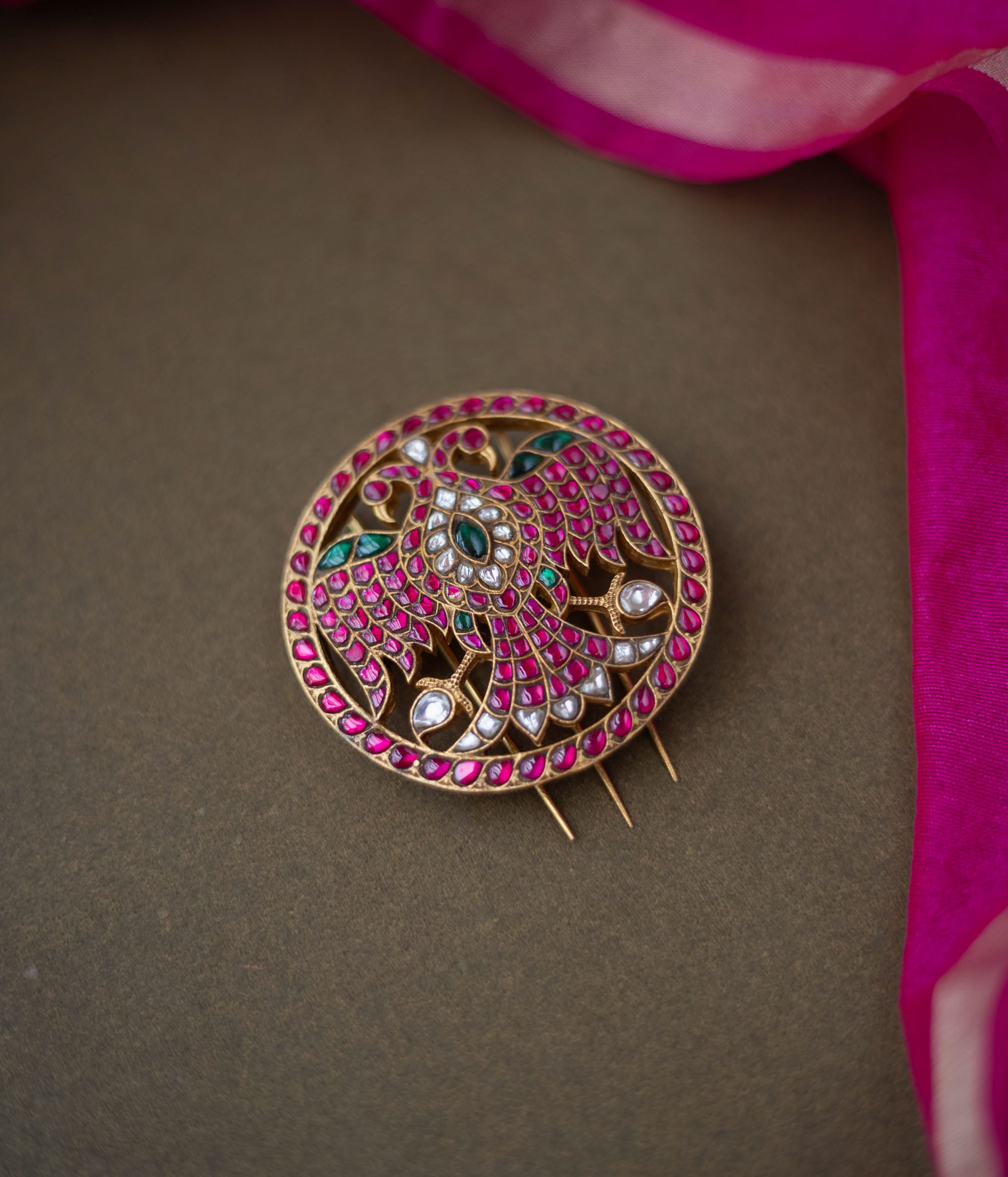 Bird motif Nayika Kundan Hairpin with red, white, and green kundan stones placed on a dark surface with pink silk fabric.