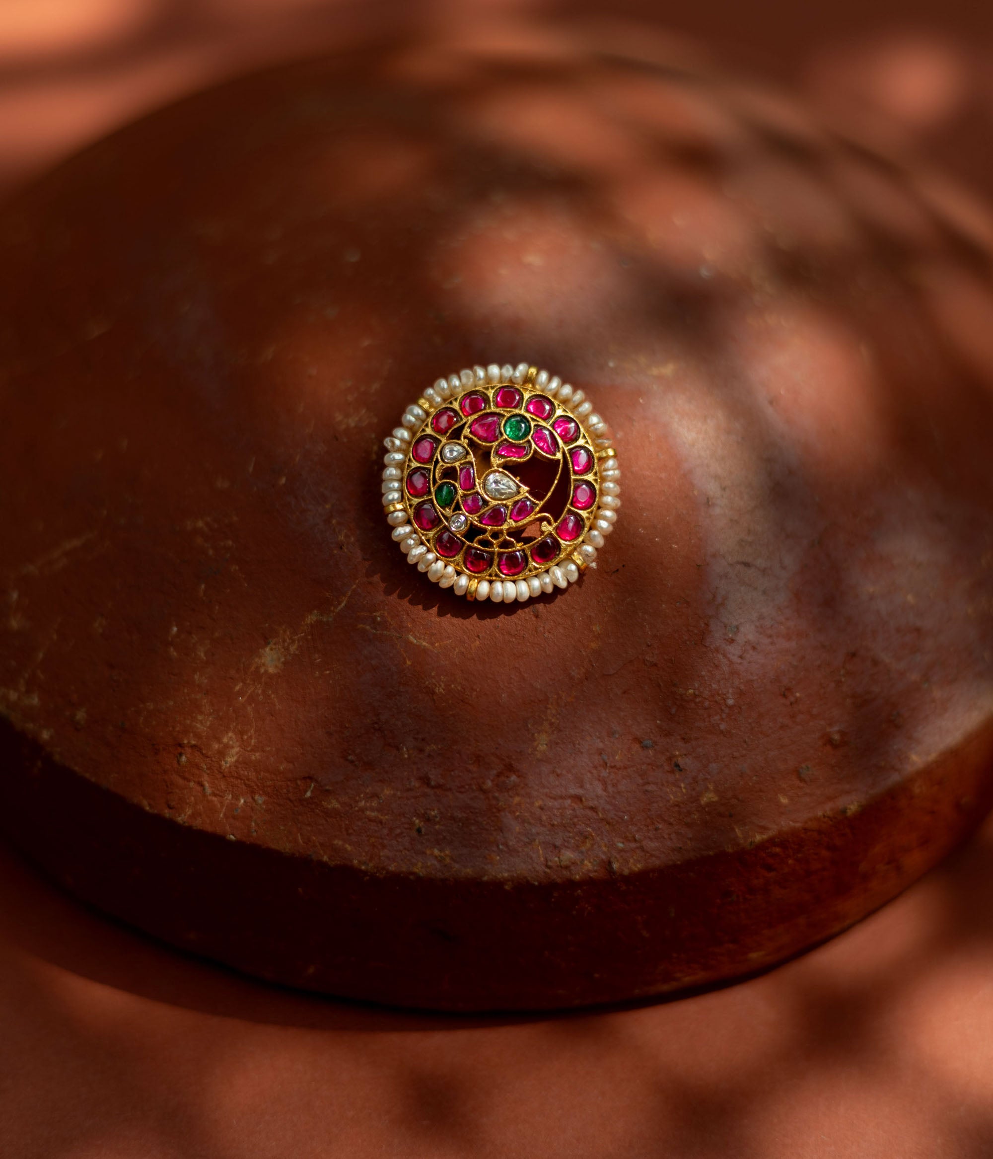 Gold-framed hairpin with vibrant red and green kundan stones and lustrous pearls, inspired by classical Indian motifs for a regal traditional hairstyle.
