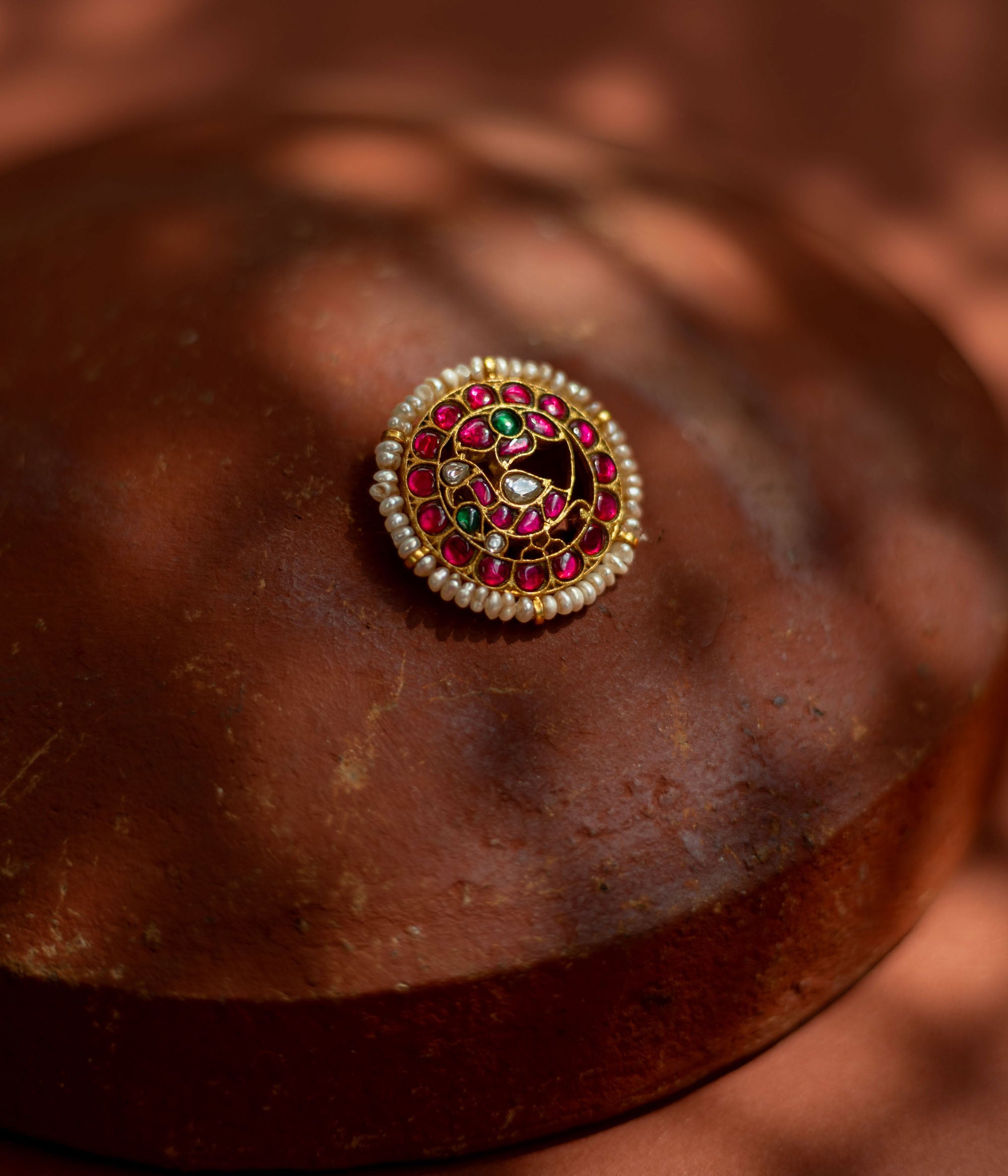 Gold-framed hairpin with vibrant red and green kundan stones and lustrous pearls, inspired by classical Indian motifs for a regal traditional hairstyle.
