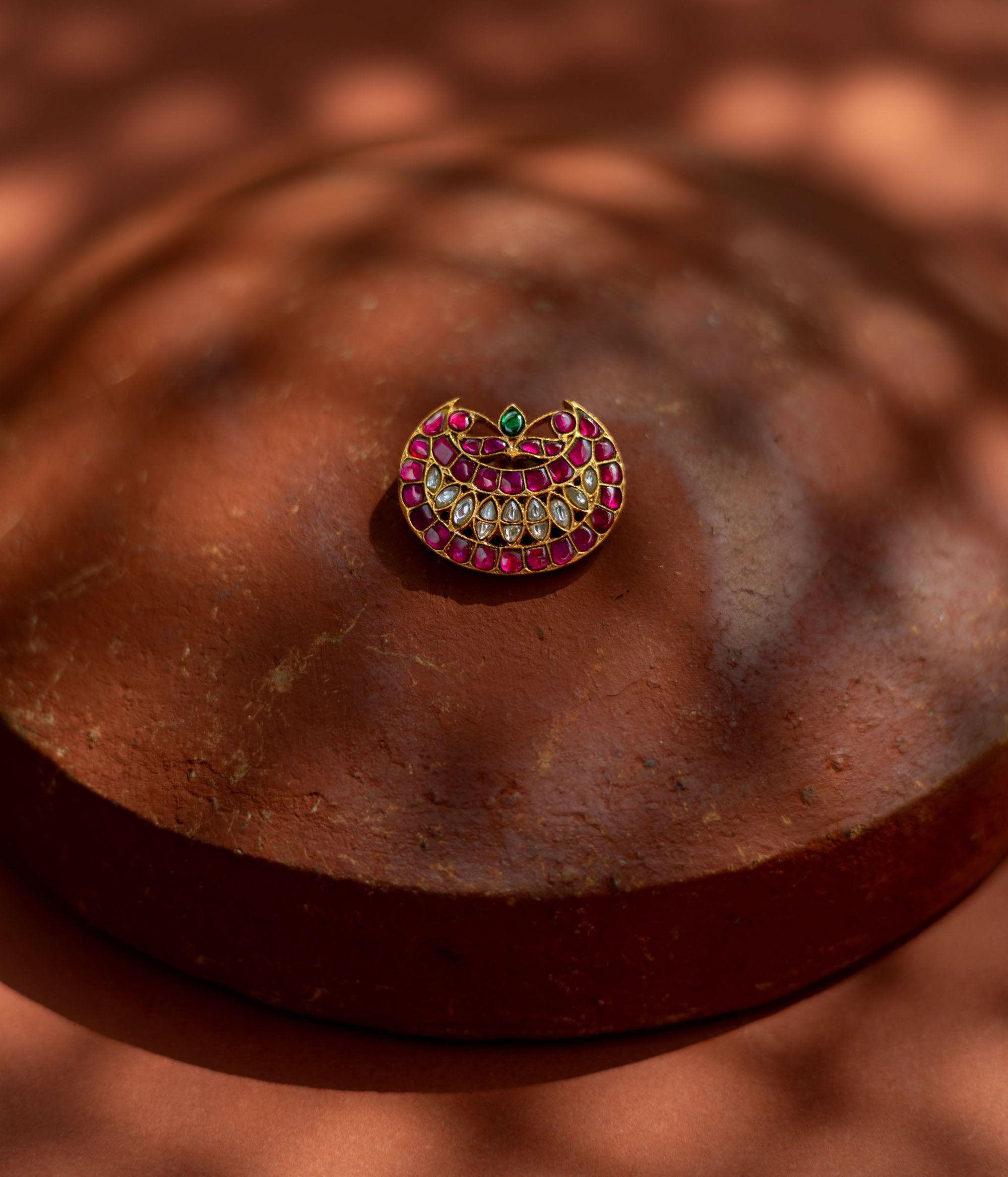 Crescent-shaped hairpin with rich pink and white kundan stones and a single emerald green accent, symbolizing youth and radiance for ethnic ensembles.