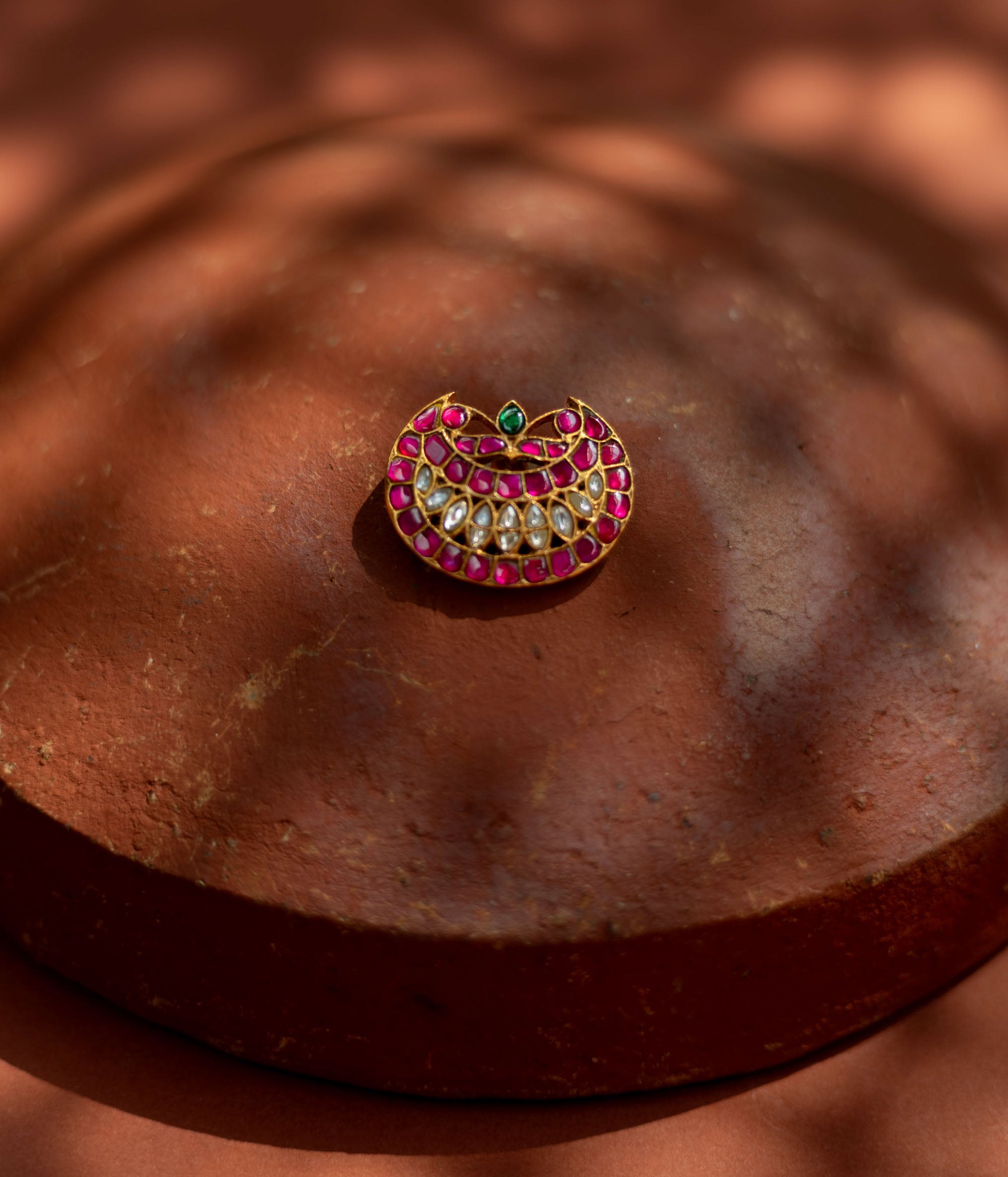 Crescent-shaped hairpin with rich pink and white kundan stones and a single emerald green accent, symbolizing youth and radiance for ethnic ensembles.