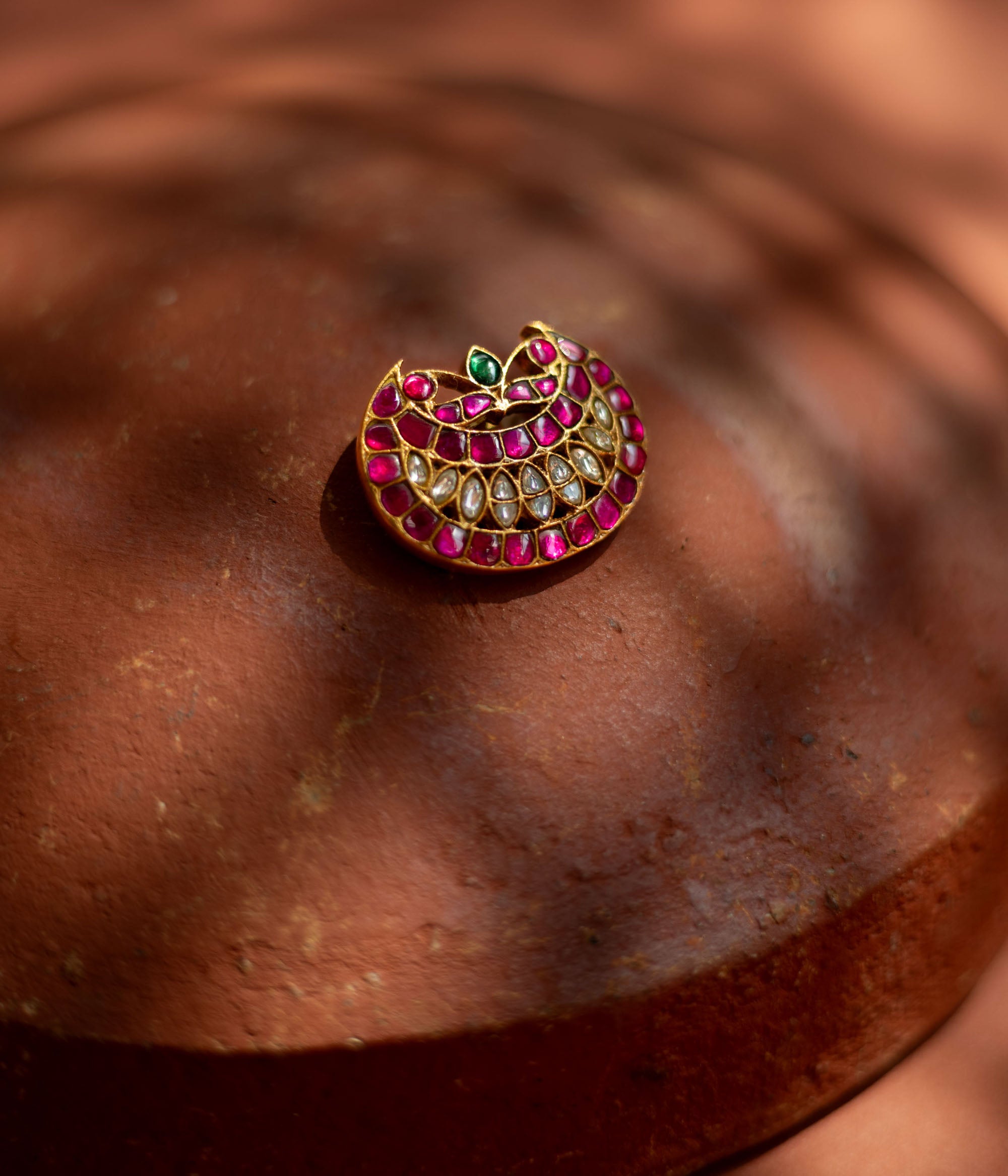 Crescent-shaped hairpin with rich pink and white kundan stones and a single emerald green accent, symbolizing youth and radiance for ethnic ensembles.