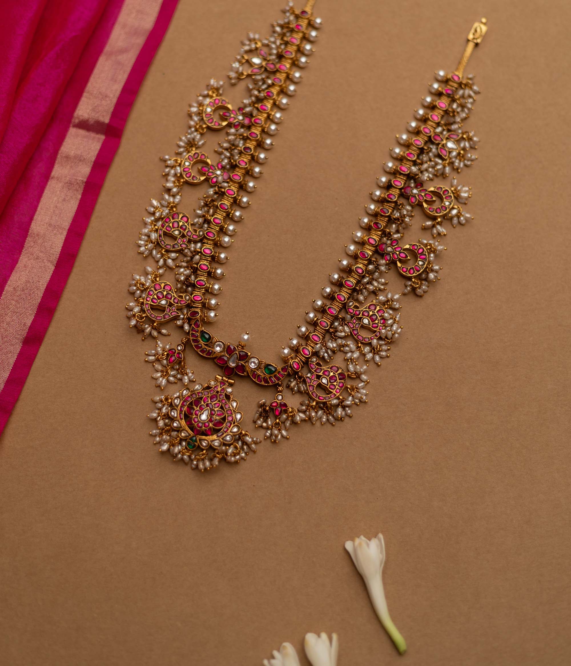 Grand temple-inspired Kundan necklace with shimmering stones, vibrant ruby and emerald accents, and delicate pearl clusters, perfect for weddings and divine celebrations.